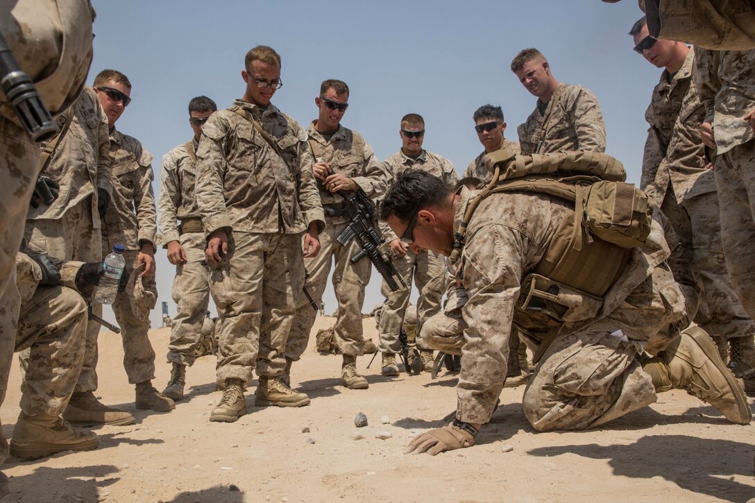 KUWAIT (Aug. 28, 2015) U.S. Marine 1st Lt. Gregory Namrow kneels down to adjust a terrain model as he briefs his Marines on a scheme of maneuver during sustainment training through an urban environment. Namrow is a platoon commander with Kilo Company, Battalion Landing Team, 3rd Battalion, 1st Marine Regiment, 15th Marine Expeditionary Unit. During the training, Marines learned how to incorporate an M1A1 Abrams tank in squad attacks in an urban environment. Elements of the 15th MEU are ashore in Kuwait for sustainment training to maintain and enhance the skills they developed during their pre-deployment training period The 15th MEU is embarked aboard the Essex Amphibious Ready Group and deployed to maintain regional security in the U.S. 5th Fleet area of operations. (U.S. Marine Corps photo by Sgt. Emmanuel Ramos/Released)