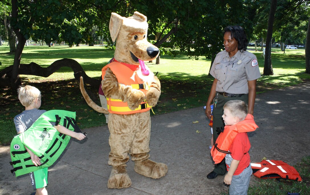Bobber the Water Safety Dog and U.S. Army Corps of Engineers' Park Ranger Angela Jones help instruct two children the proper way to wear a water safety vest during the Fort DeRussy beach and berm cleanup for National Public Lands Day. The Corps of Engineers’ Pacific Regional Visitor Center (RVC) coordinated the event which was supported by Corps employees, U.S. Army Transporters from the 545th Transportation Company, and Punahou Junior ROTC cadets.   National Public Lands Day is the largest single-day volunteer effort for public lands in the U.S. It began in 1994 and focuses on education and partnerships to care for the nation’s natural treasures. 