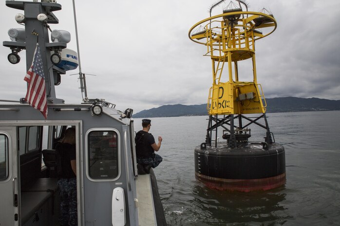 Seaman Halon Hamilton, maintenance man aboard the boat with Harbor Operations, guides the driver up to a buoy during a training evolution aboard Marine Corps Air Station Iwakuni, Japan, Sept. 2, 2015. Walking the boat up to a buoy simulates pulling into a narrow berth or alongside a pier.(U.S. Marine Corps photo by Lance Cpl. Nicole Zurbrugg/Released)
