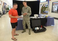Airman Brian Tripp, 36th Civil Engineer Squadron emergency management apprentice, speaks with a Team Andersen member Sept. 22, 2015, at Andersen Air Force Base, Guam. Emergency managers set up a static display and informed base exchange patrons about Andersen AFB disaster response and recovery operations during National Preparedness Month. (U.S. Air Force photo by Senior Airman Joshua Smoot/Released)