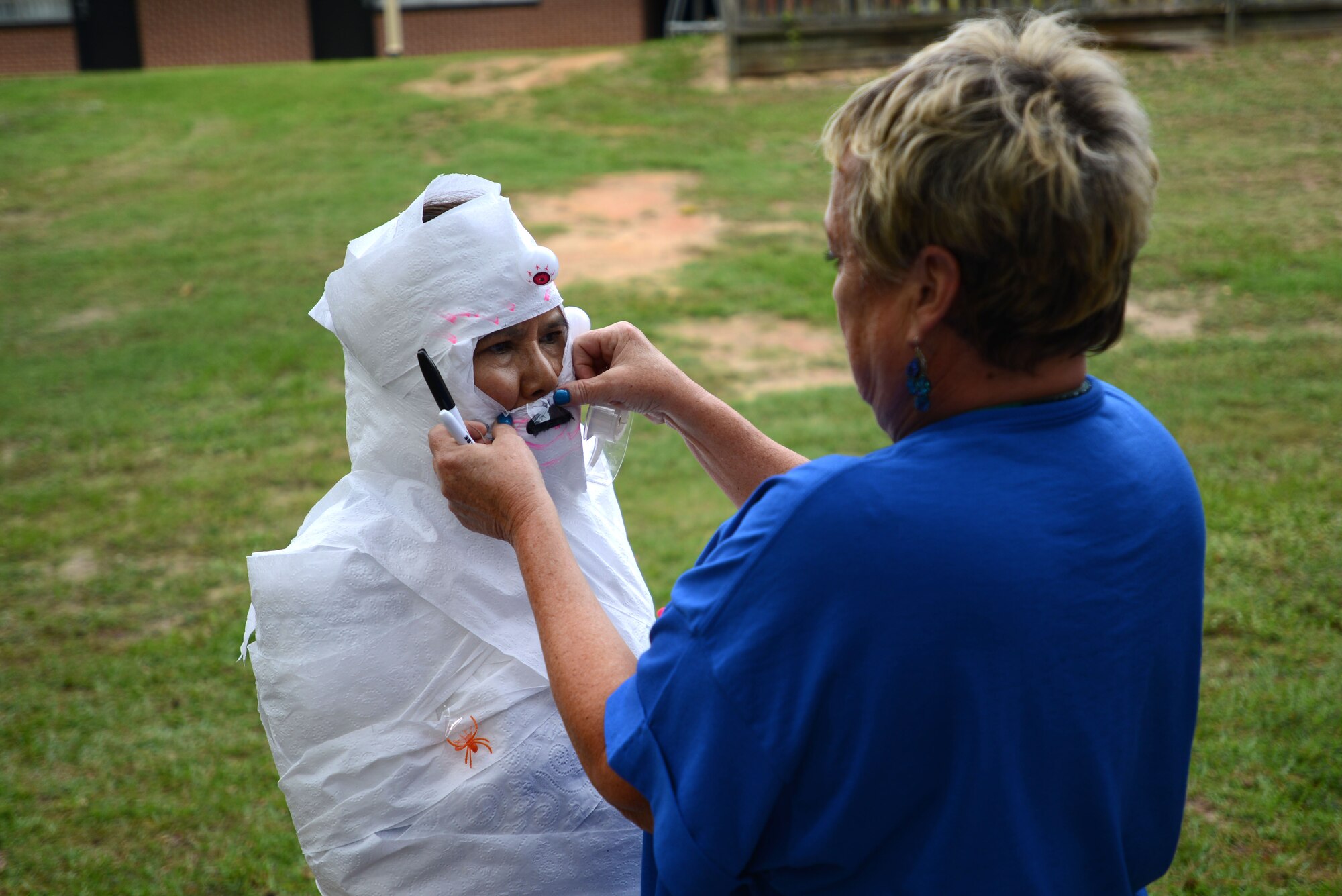 Lek Sullivan, 20th Force Support Squadron custodial worker, stands patiently as Martha Wright, 20th FSS custodial worker supervisor, tapes a fake moustache to her during the mummy-wrapping contest during International Housekeeping Week at Shaw Air Force Base, S.C., Sept. 16, 2015. The weeklong event consisted of several housekeeping-themed games for the staff to participate in, with prizes for the winners. (U.S. Air Force photo by Airman 1st Class Kelsey Tucker/Released)
