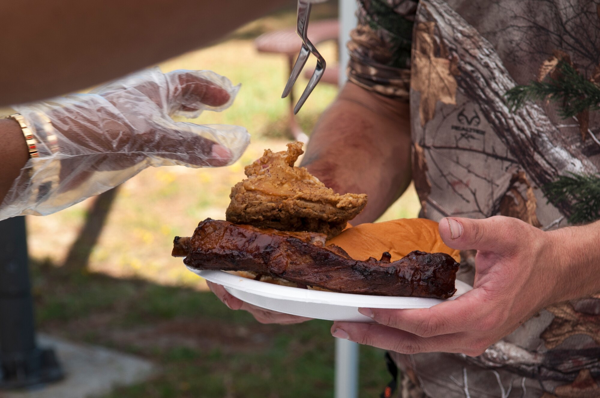 A member of Team Seymour gets food from a volunteer during a dorm dwellers barbecue event, Sept. 19, 2015, at Seymour Johnson Air Force Base, North Carolina. Twice a year, the 4th Fighter Wing Chaplain Corps’ Protestant Men of the Chapel hosts a barbecue for all dorm Airmen as a means of raising their spiritual resilience. (U.S. Air Force photo/Airman 1st Class Shawna L. Keyes)