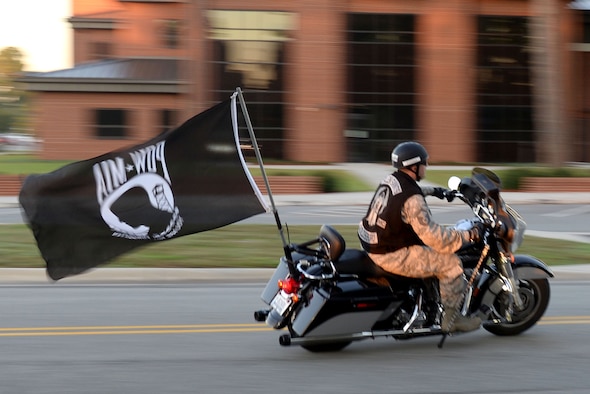 Master Sgt. Benjamin Ackerman, 4th Contracting Squadron contracting officer, flies a flag from the back of his motorcycle during the Prisoners of War/Missing in Action 5K, Sept. 14, 2015, at Seymour Johnson Air Force Base, North Carolina. Ackerman led other motorcyclists and participating Airmen as they navigated their way through base during the 5K run. (U.S. Air Force photo/Airman 1st Class Ashley Williamson)