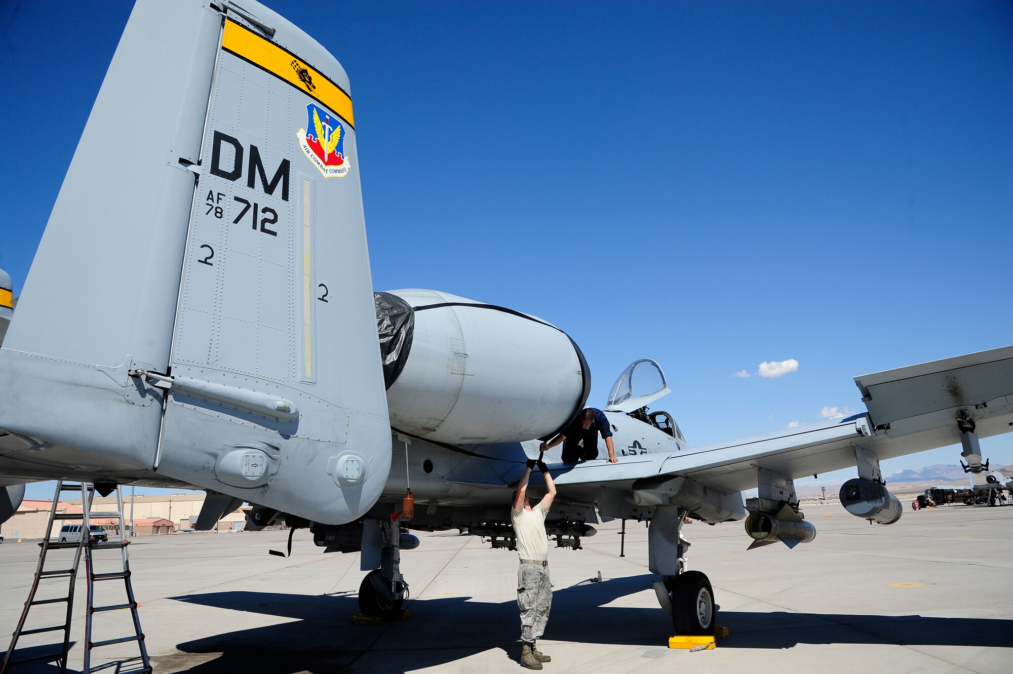 U.S. Air Force Staff Sgt. Patrick Peloquin and Airman 1st Class Michael Soto, 355th Aircraft Maintenance Squadron crew chiefs, connect a buckle to a soft cover to protect an A-10 Thunderbolt II engine at Nellis Air Force Base, Nev., Sept. 16, 2015.  The 355th AMXS and the 357th Fighter Squadron from Davis-Monthan AFB, Ariz., visited Nellis AFB to participate in Green Flag-West 15-10. (U.S. Air Force photo by Senior Airman Betty R. Chevalier/Released)