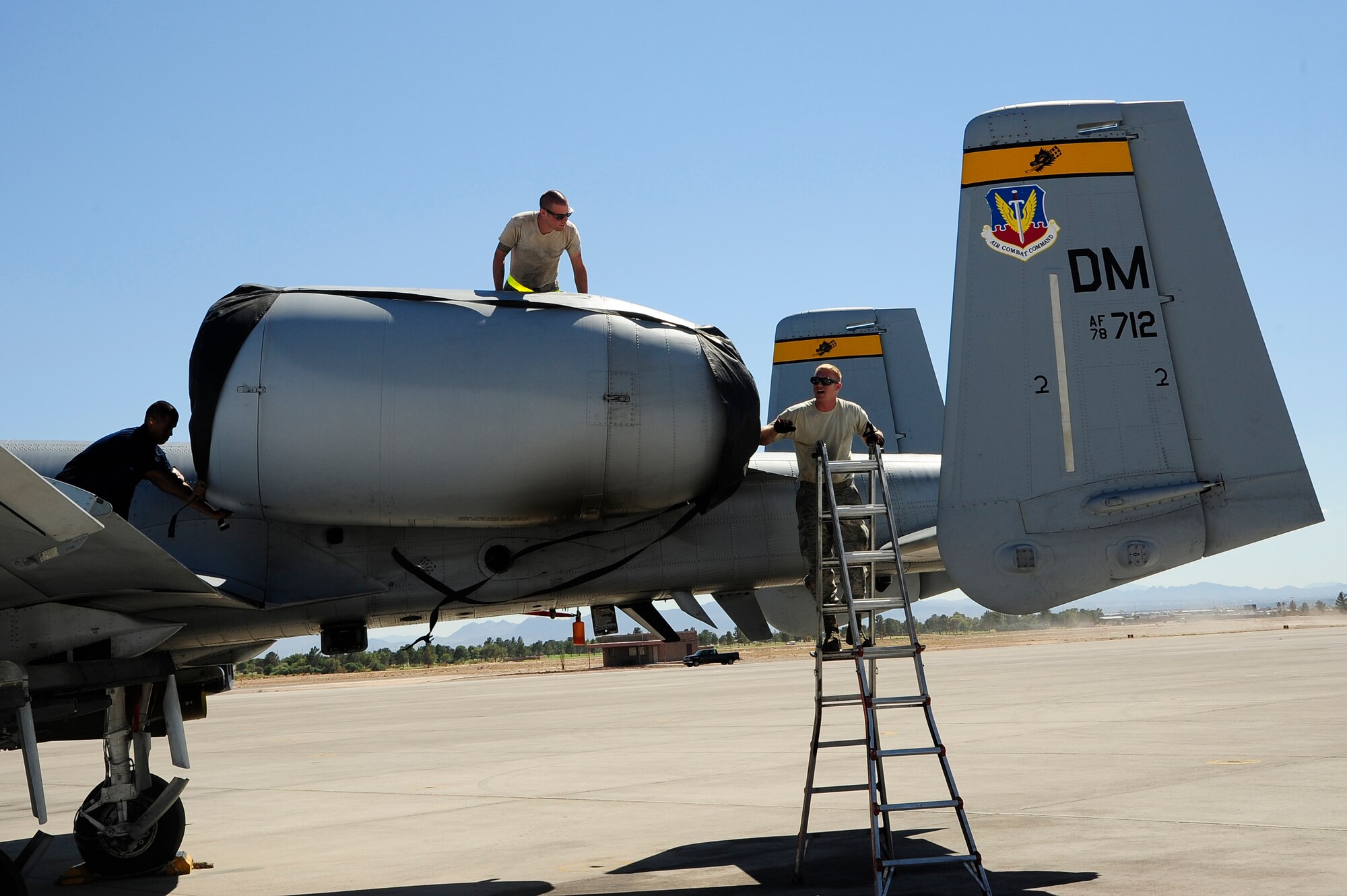 U.S. Airmen assigned to the 355th Aircraft Maintenance Squadron at Davis-Monthan Air Force Base, Ariz., work together to put a soft cover over the engine of an A-10 Thunderbolt II at Nellis AFB, Nev., Sept. 16, 2015.  Pilots from D-M’s 357th Fighter Squadron have been flying missions for Green Flag- West 15-10, a joint combat air support integration exercise. (U.S. Air Force photo by Senior Airmen Betty R. Chevalier/Released)