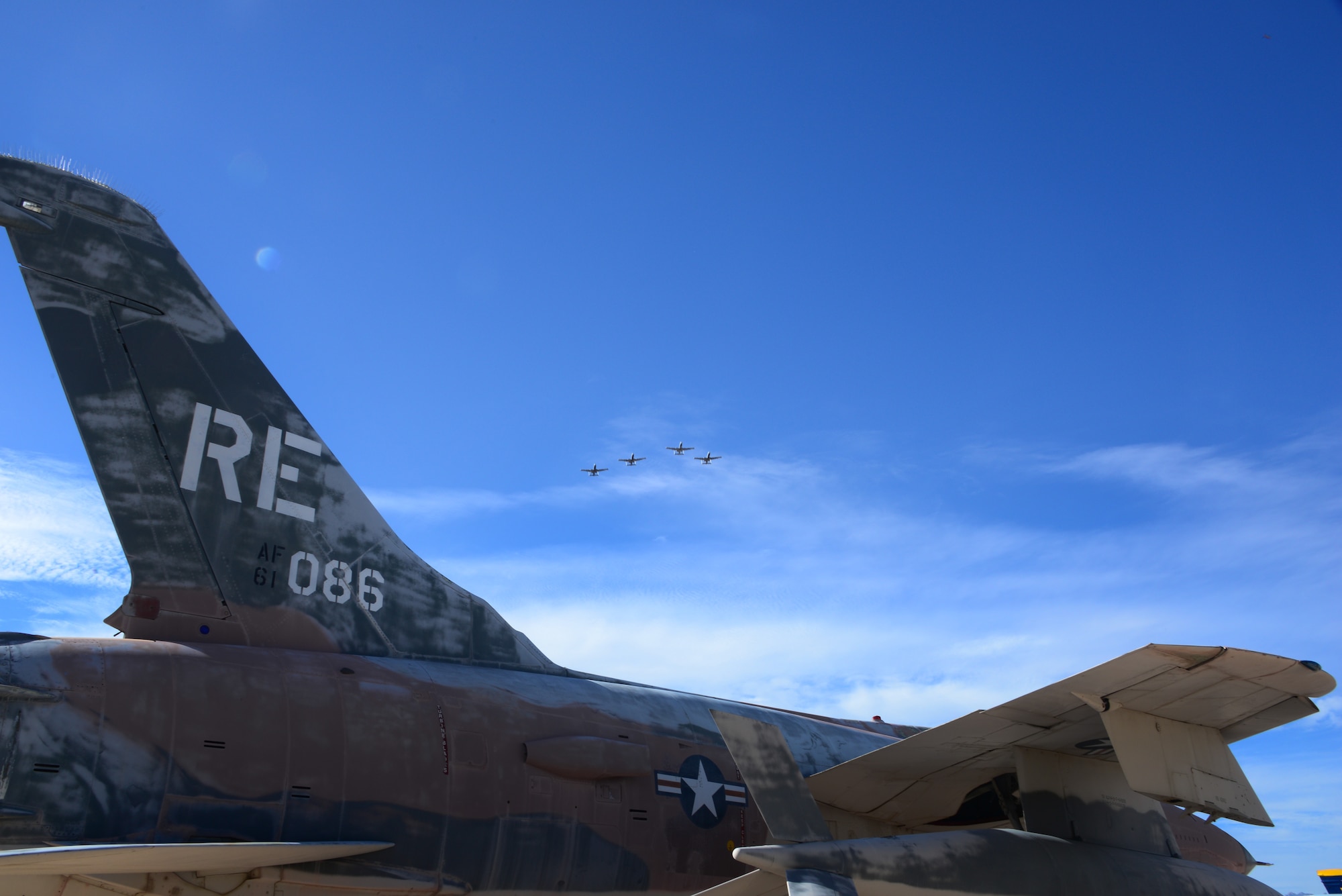 An F-105 Thunderchief sits on display as four U.S. Air Force A-10C Thunderbolt IIs from the 357th Fighter Squadron perform a missing man flyover at the Pima Air and Space Museum in Tucson, Ariz., Sept. 18, 2015. The flyover concluded a POW/MIA Remembrance Ceremony held to honor prisoners of war and those who are still missing in action. During the flyover a single A-10 broke away from the rest of the four ship to symbolize those who are still missing. (U.S. Air Force photo by Senior Airman Cheyenne A. Powers/ Released) 