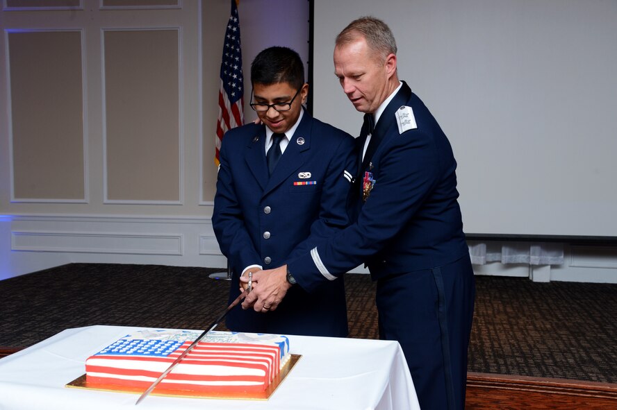 U.S. Air Force Airman 1st Class Israel Marrufo, 20th Equipment Maintenance Squadron aircraft structural maintenance apprentice, and Maj. Gen. Mark Kelly, Ninth Air Force commander, cut the birthday cake with a saber at the Shaw Air Force Ball at Shaw Air Force Base, S.C., Sept. 18, 2015. Tradition dictates that the oldest and the youngest Airmen in attendance cut the cake during the ball. (U.S. Air Force photo by Senior Airman Jonathan Bass/Released)