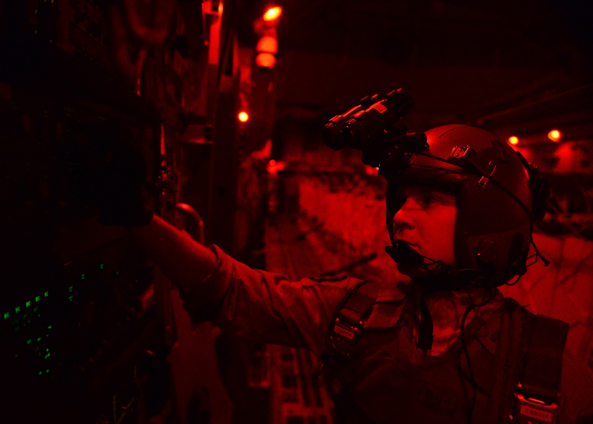 Senior Airman Paul Maginnis prepares to open the back door on a C-17 Globemaster III during a humanitarian air drop of 40 container delivery system bundles filled with fresh drinking water Aug. 31, 2014, over the area of Amirli, Iraq. Lights are dimmed or shut off completely to lower visibility to threats from the ground. The airdrop included two C-17s and two C-130 Hercules delivering 10,545 gallons of fresh drinking water and 7,056 Halal Meals Ready to Eat. Maginnis is a 816th Expeditionary Airlift Squadron loadmaster. (U.S. Air Force photo/Staff Sgt. Shawn Nickel)