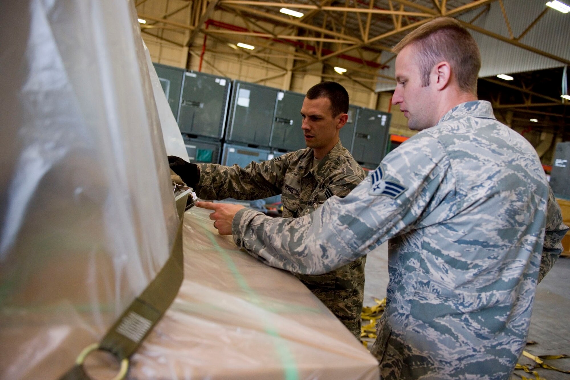 Senior Airman Holcomb, 49th Aerial Port Flight aerial port journeyman, and Senior Airman Thomas Wewel, 49th APF aerial port apprentice, check to ensure palletized food for a humanitarian mission is properly secured at Grissom Air Reserve Base, Ind., Sept. 12 2015.  Grissom Airman stepped up to help deliver 43,000 pounds of food to over 8,500 Haitians as part of the Denton Program. (U.S. Air Force photo /Senior Airman Jami K. Lancette)