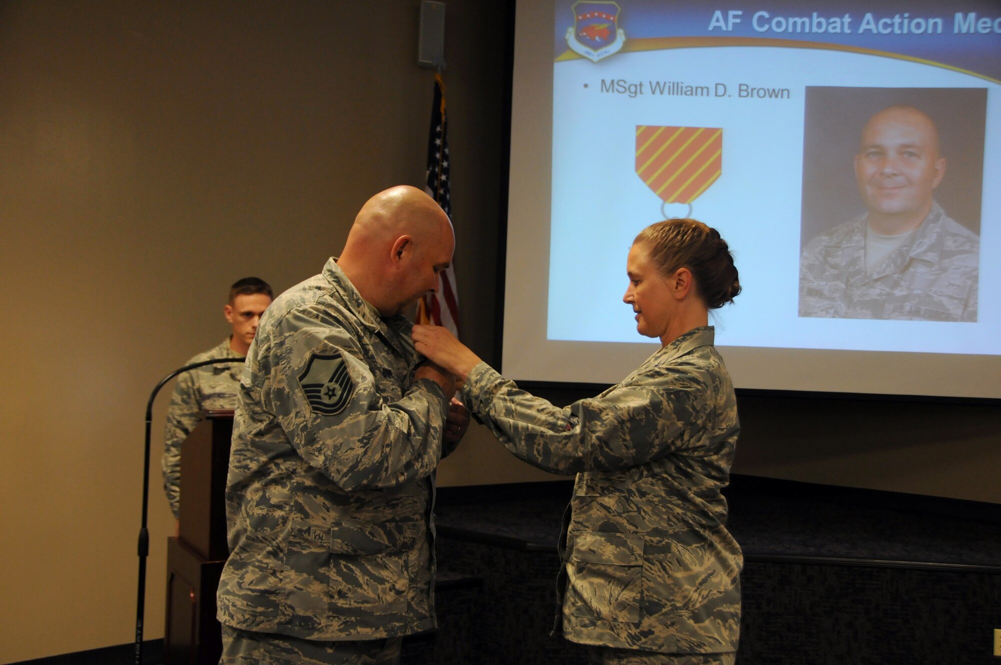Master Sgt. William Brown is pinned the Air Force Combat Action Medal Sept. 19, 2015, by Col. Bobbi Doorenbos, 188th Wing commander at Ebbing Air National Guard Base, Fort Smith, Ark. As a gun truck commander in Iraq, Brown was responsible for a supply convoy that was fired upon by enemy personnel on June 3, 2005. Col. Bobbi Doorenbos, 188th Wing commander, bestowed the award to Brown for his active participation in combat, having been under direct and hostile fire in connection with military operations. (U.S. Air National Guard photo by Senior Airman Cody Martin/Released)