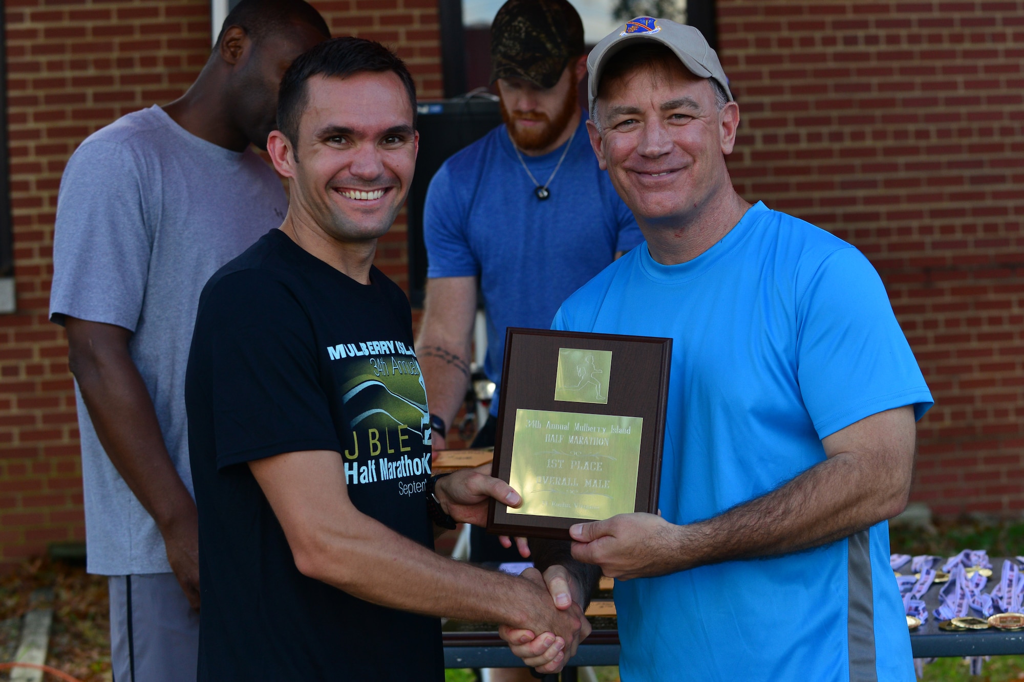 U.S. Army Col. William S. Galbraith, 733rd Mission Support Group commander, right, awards the first place overall male Mulberry Island Half Marathon plaque to Capt. Bryce Livingston, 7th Sustainment Brigade terminal operations officer, at Fort Eustis, Va., Sept. 19, 2015. Livingston finished not only first in his category, but in the race with a time of 1:13:28. (U.S. Air Force photo by Staff Sgt. Natasha Stannard/Released)