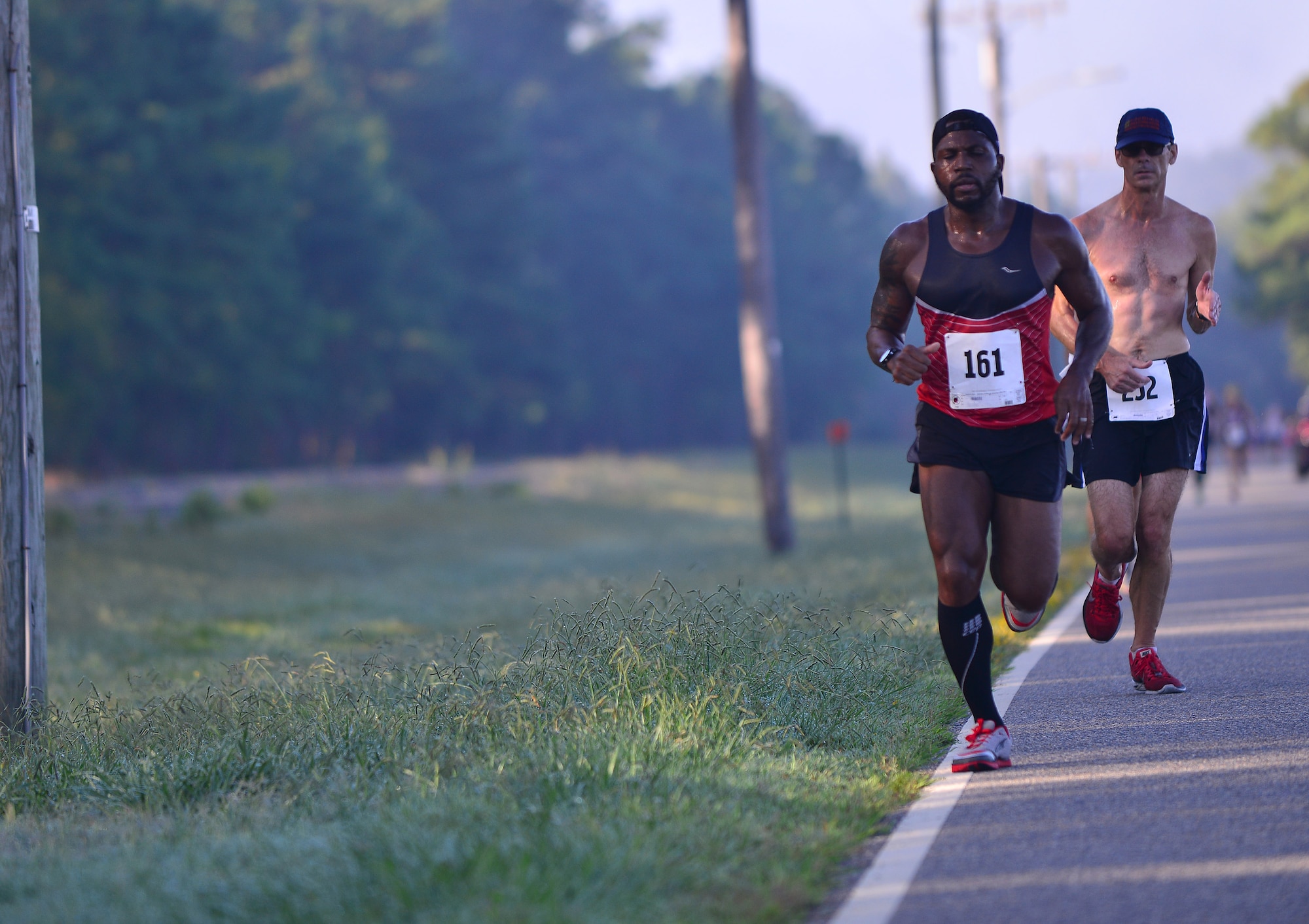 Andrew D. Cutler of Yorktown, Va., back, catches up to Sandifer Cardave of Virginia Beach, Va., during the Mulberry Island Half Marathon at Fort Eustis, Va., Sept. 19, 2015. Both Cutler and Cardave averaged under a seven minute-per-mile pace, and placed in their age groups. (U.S. Air Force photo by Staff Sgt. Natasha Stannard/Released)
