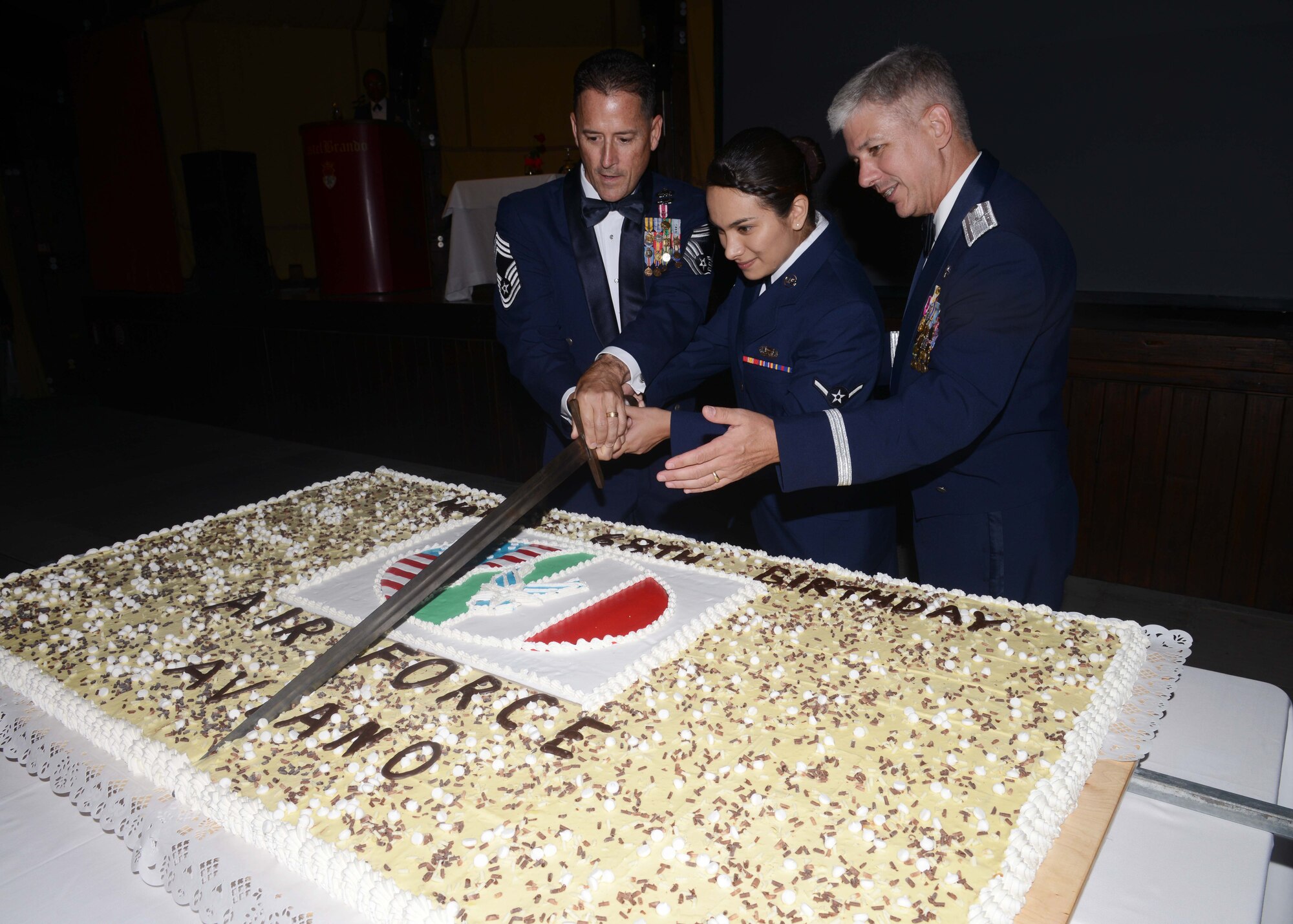 U.S. Air Force Chief Master Sgt. Steven Bowersox, 31st Munitions Squadron superintendent, Airman Danielle Freire, 31st Force Support Squadron force management journeyman, and Brig. Gen. Barre Seguin, 31st Fighter Wing commander, cuts the Air Force birthday cake, Sept. 18, 2015, at Castel Brando in Cison di Valmarino, Italy. This tradition symbolizes the wisdom of the oldest Airmen being passed down to the youngest. (U.S. Air Force photo by Senior Airman Deana Heitzman/Released)     