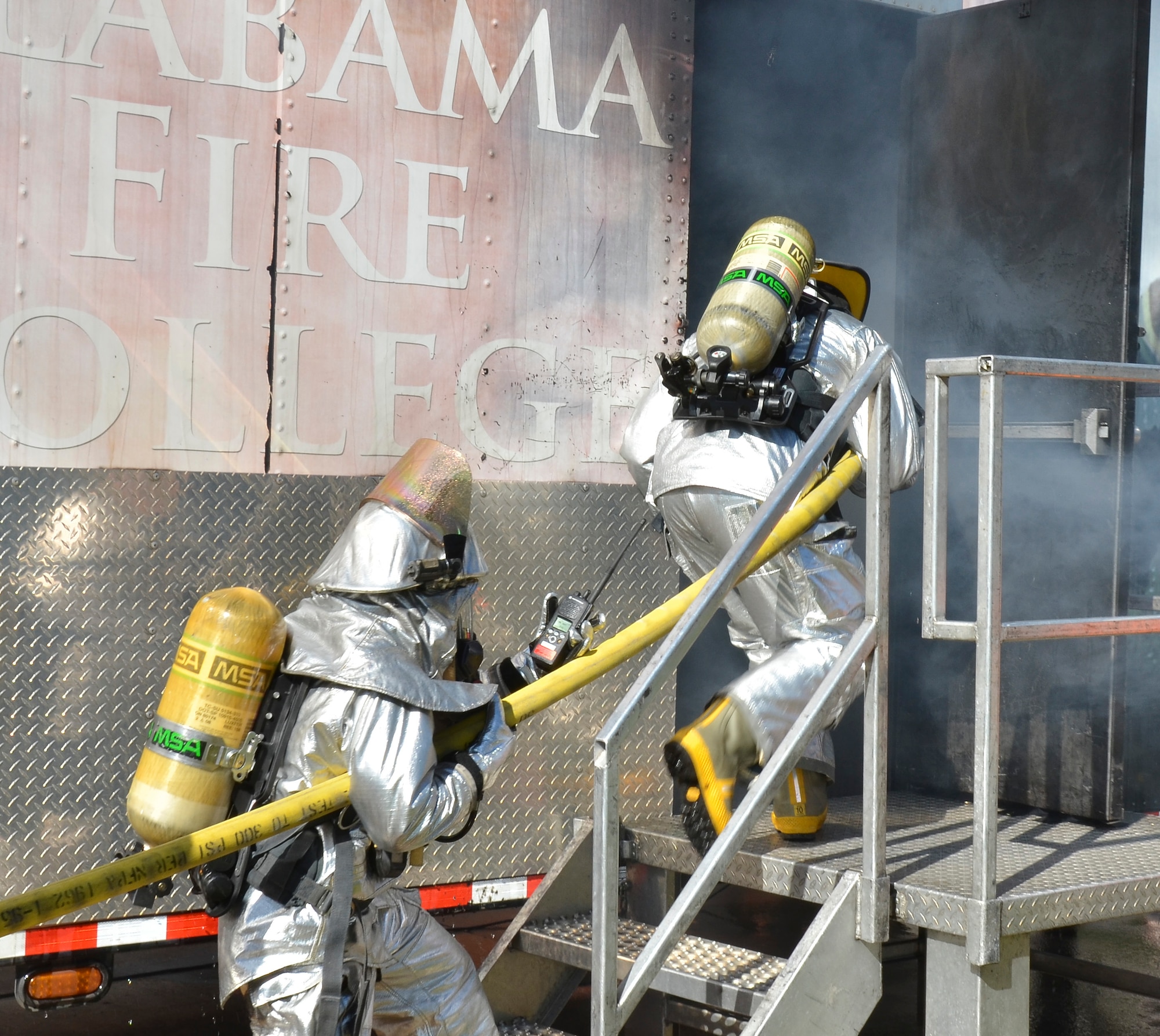 Firefighters from the Civil Engineering Squadron practice fighting structure fires as a part of their annual training at the 117th Air Refueling Wing on September 19, 2015. The firefighters used a travel trailer and other equipment to simulate structure fires caused by propane gas. According to Master Sgt. Brian Garvich, their main strategy in fighting these fires was to utilize the “two-in, two-out” policy which mandates that firefighters never enter a building alone during a rescue mission. Two firefighters act as a team entering the structure and another two-person team is waiting outside the hazard dedicated to rescuing those inside, should they need it. (U.S. Air National Guard photo  by Staff Sgt. Jeremy Farson/Released)