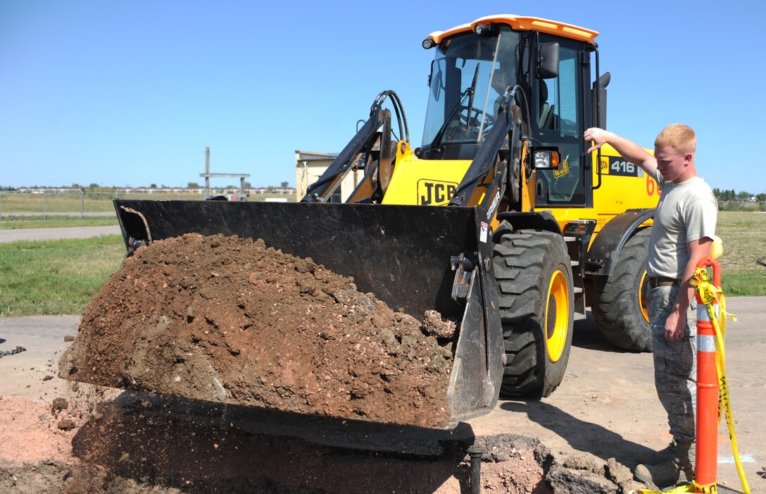 Senior Airman Dustin Snyder, 28th Civil Engineer Squadron pavements and construction technician, signals to dump dirt at a main fuel storage tank site on Ellsworth Air Force Base, S.D., Sept. 2, 2015. Preventative measures are taken to confirm there are no leaks or spills, ensuring a clean and healthy environment. (U.S. Air Force photo by Airman Sadie Colbert/Released)