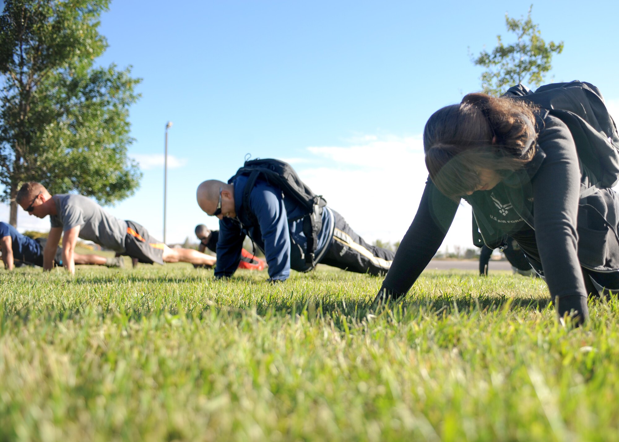 Second Lt. Corey Hayes, 28th Force Support Squadron readiness officer in charge (left), Capt. Benjamin Quintanilla, 28th Bomb Wing chaplain (center), and Senior Airman Lucile Perkinswagle, 28th FSS fitness center journeyman (right), perform pushups as a part of a ruck march at Ellsworth Air Force Base, S.D., Sept. 18, 2015. Approximately 10 Airmen participated in the challenge aimed at encouraging unit cohesion and critical thinking. (U.S. Air Force photo by Airman Sadie Colbert/Released)