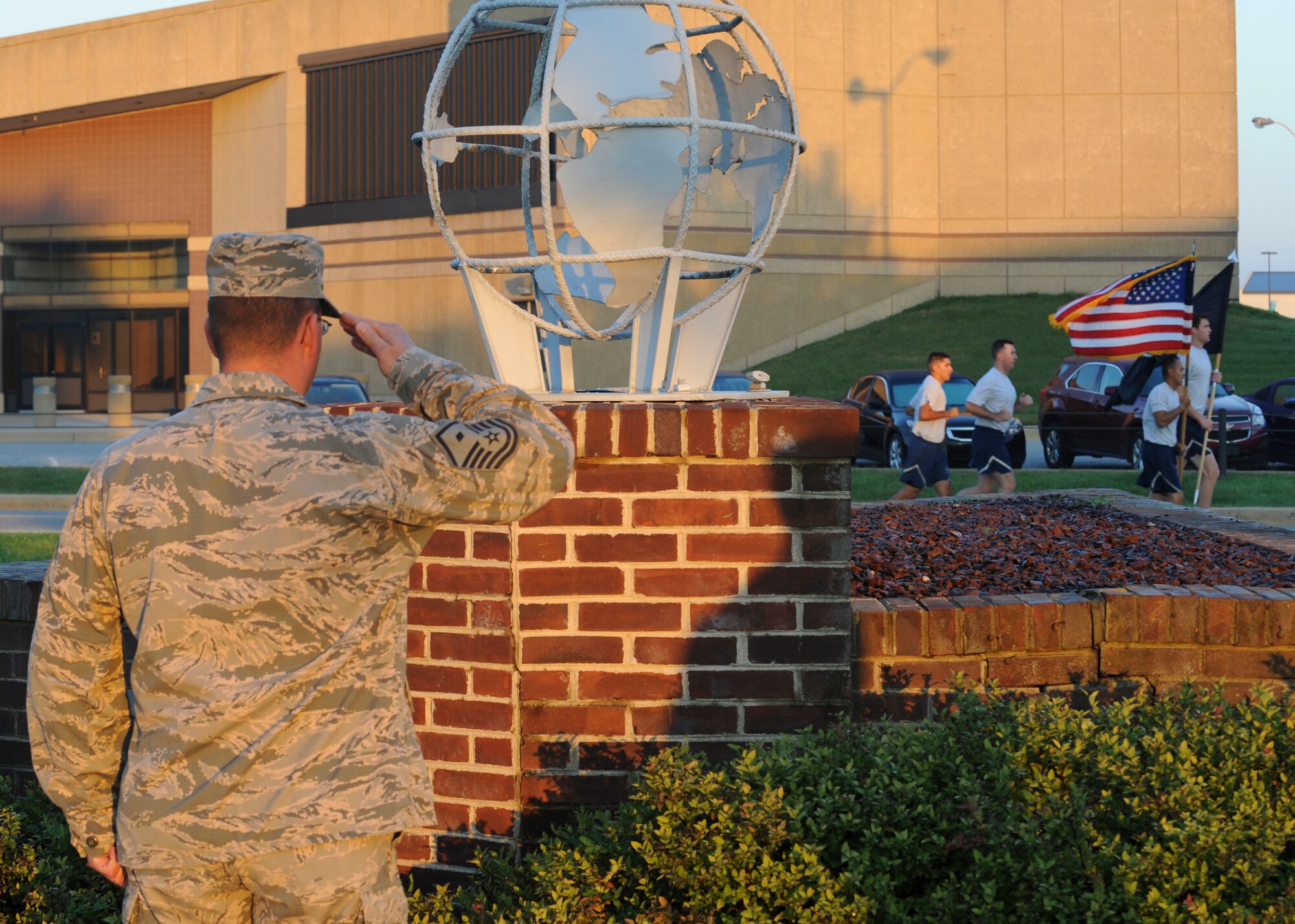 Master Sgt. Anthony Christ, 436th Operations Support Squadron first sergeant, salutes as members of Team Dover run by with the U.S. and POW/MIA flags during the National POW/MIA Recognition Day vigil Sept. 18, 2015, at Dover Air Force Base, Del. Christ stood guard at the base flag pole along with other first sergeants for 10-minute rotations during the vigil. (U.S. Air Force photo/Senior Airman William Johnson) 