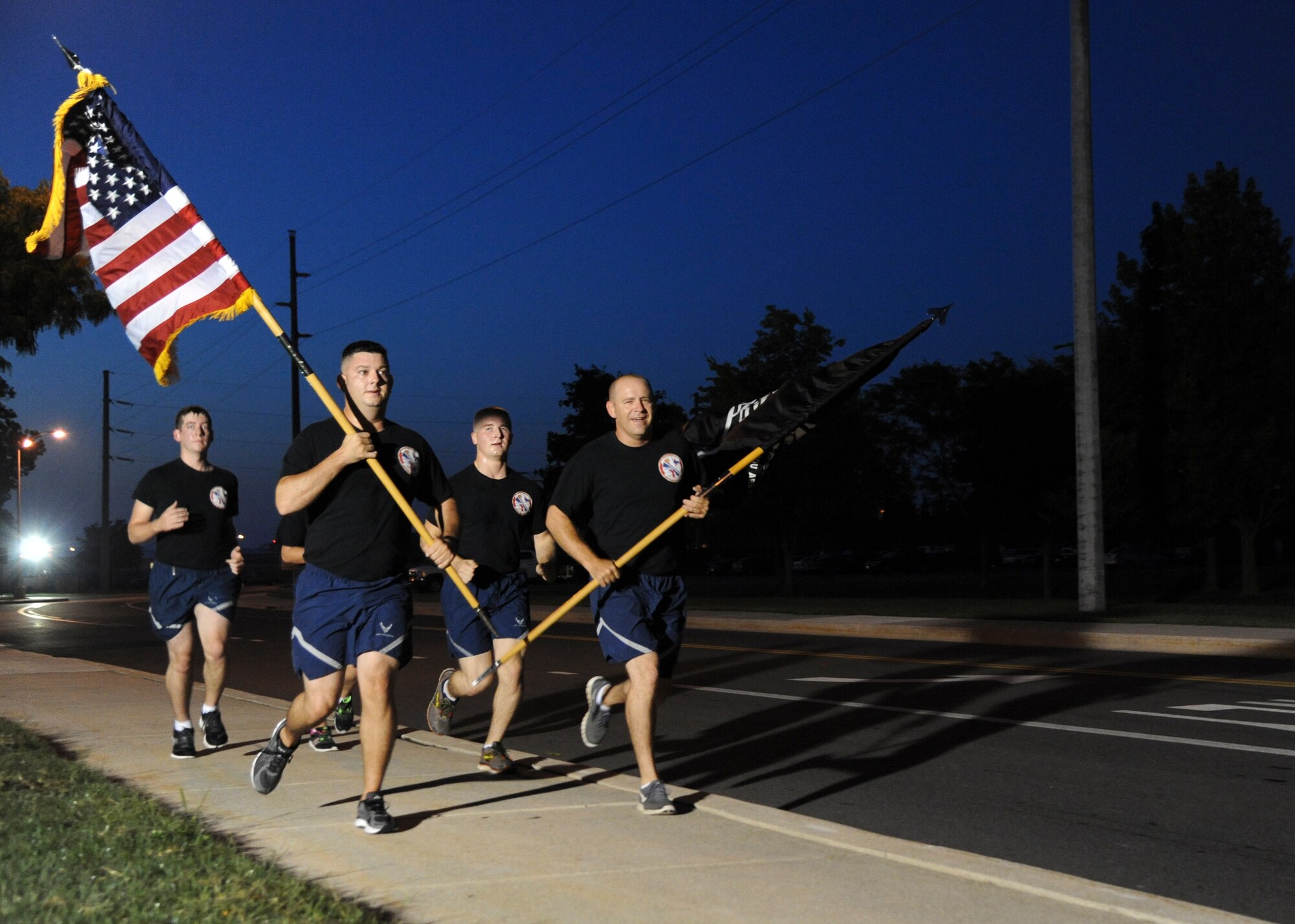 Team Dover Airmen run with the U.S. and POW/MIA flag during the National POW/MIA Recognition Day Memorial Run Sept. 18, 2015, at Dover Air Force Base, Del. National POW/MIA Recognition Day is annually observed in the United States on the third Friday of September. (U.S. Air Force photo/Senior Airman William Johnson)