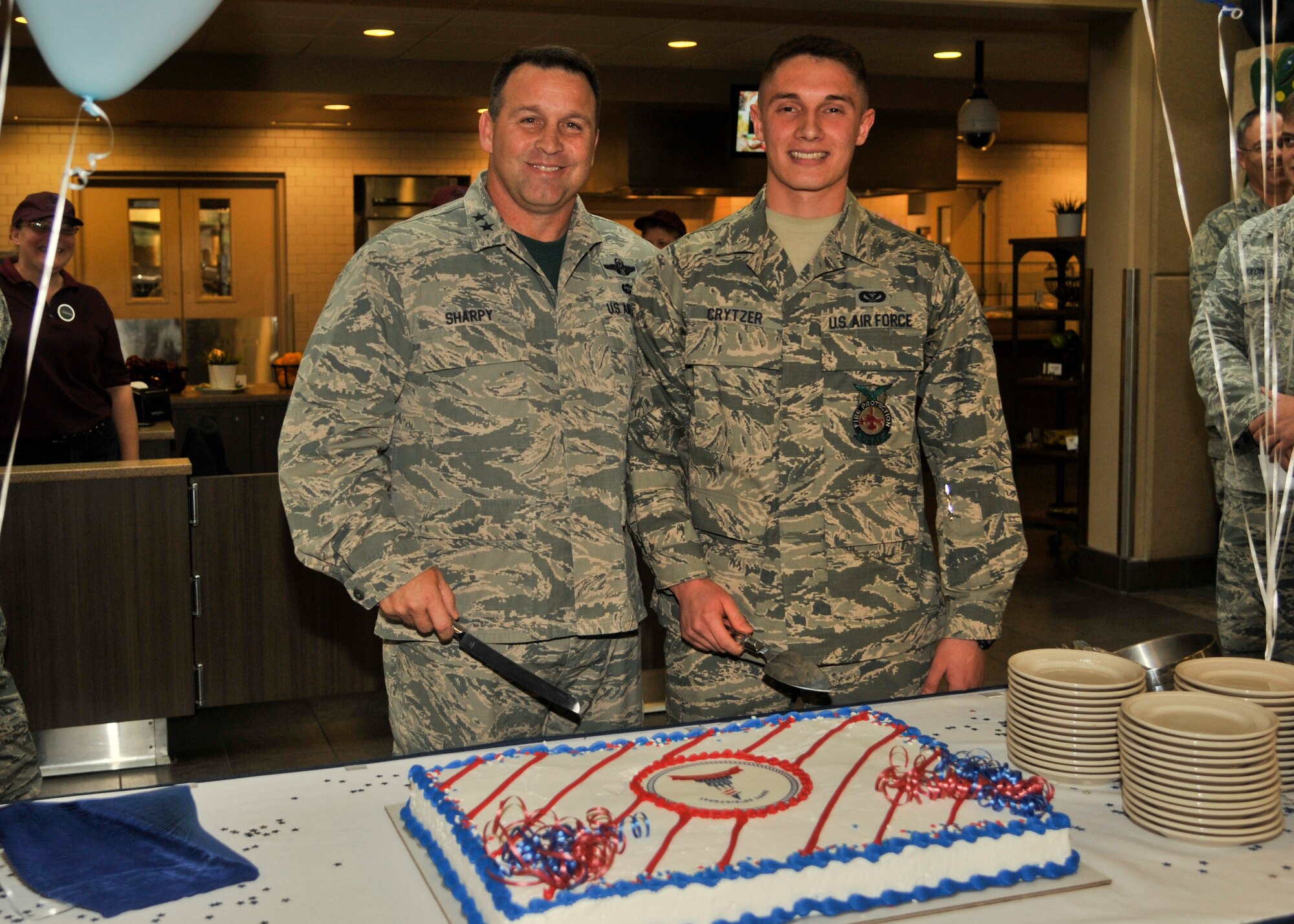 Maj. Gen. Thomas J. Sharpy, 18th Air Force commander, and Airman 1st Class Logan Crytzer, 92nd Force Support Squadron firefighter, pose for a picture before they cut the cake for the Air Force birthday Sept. 18, 2015, at Fairchild Air Force Base, Wash. Crytzer, as the youngest member of the 92nd ARW, was selected to assist Sharpy in the traditional cake cutting ceremony. Since 1942, Fairchild AFB has been a key part of our nation's defense strategy from WWII as a repair depot, to a Strategic Air Command bomber wing during the Cold War, to an Air Mobility Command air refueling wing during Operations Enduring Freedom and Inherent Resolve. (U.S. Air Force photo/Airman 1st Class Taylor Bourgeous)