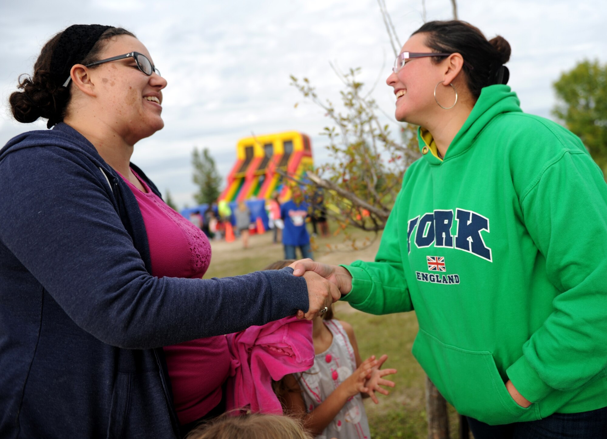 Carolina Stinson(Right), base chapel, greets Briana Trujillo at Bud Ebert Park at Minot AFB, N.D. Sept. 16, 2015. Stinson handed out information about the base chapel as part of a carnival that the chapel put on for the Airmen and their families of Minot AFB. (U.S. Air Force photo by Staff Sgt. Chad Trujillo)

