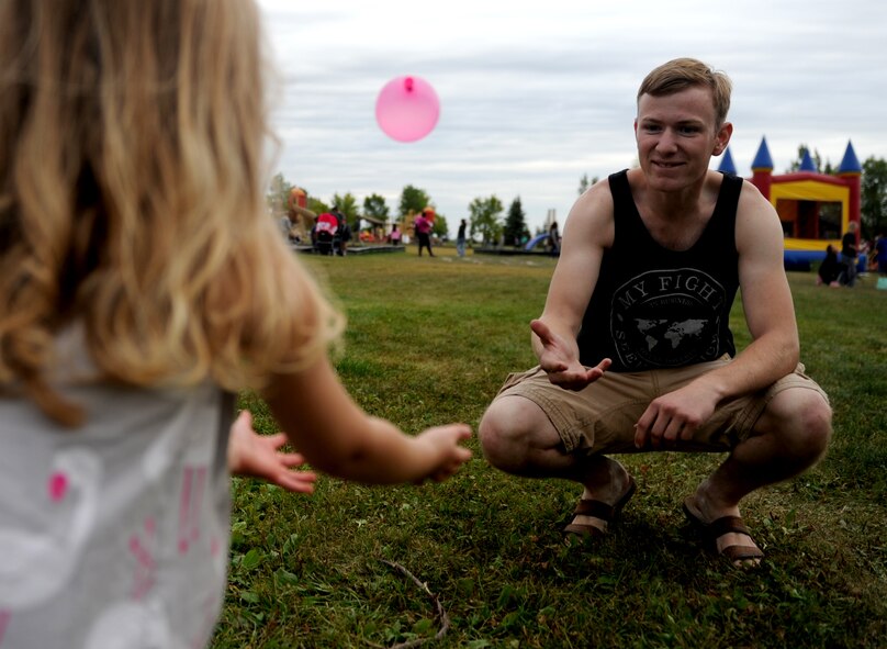 Airman 1st Class Author Rifenbury, 5th Aircraft Maintenance Squadron, plays water balloon catch with Qwynn Trujillo at Bud Ebert Park on Minot AFB, N.D. Sept. 16, 2015. Rifenbury volunteered to help with the carnival that base chapel put on for the Airmen and their families of Minot AFB. (U.S. Air Force photo by Staff Sgt. Chad Trujillo)