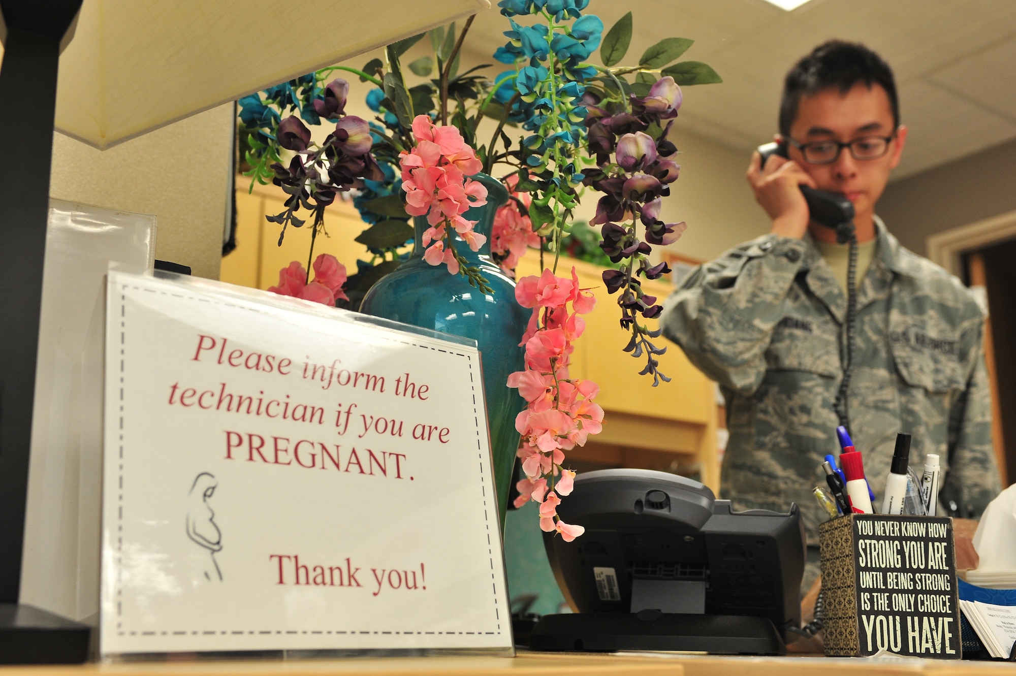 Senior Airman David Hoang, 5th Medical Operations Squadron allergy and immunizations technician, answers a call at Minot Air Force Base, N.D., Sept. 16, 2015. The Immunization Clinic offers immunizations for viruses such as the flu and smallpox as well as allergy relief and pediatric shots. (U.S. Air Force photo/Senior Airman Stephanie Morris)
