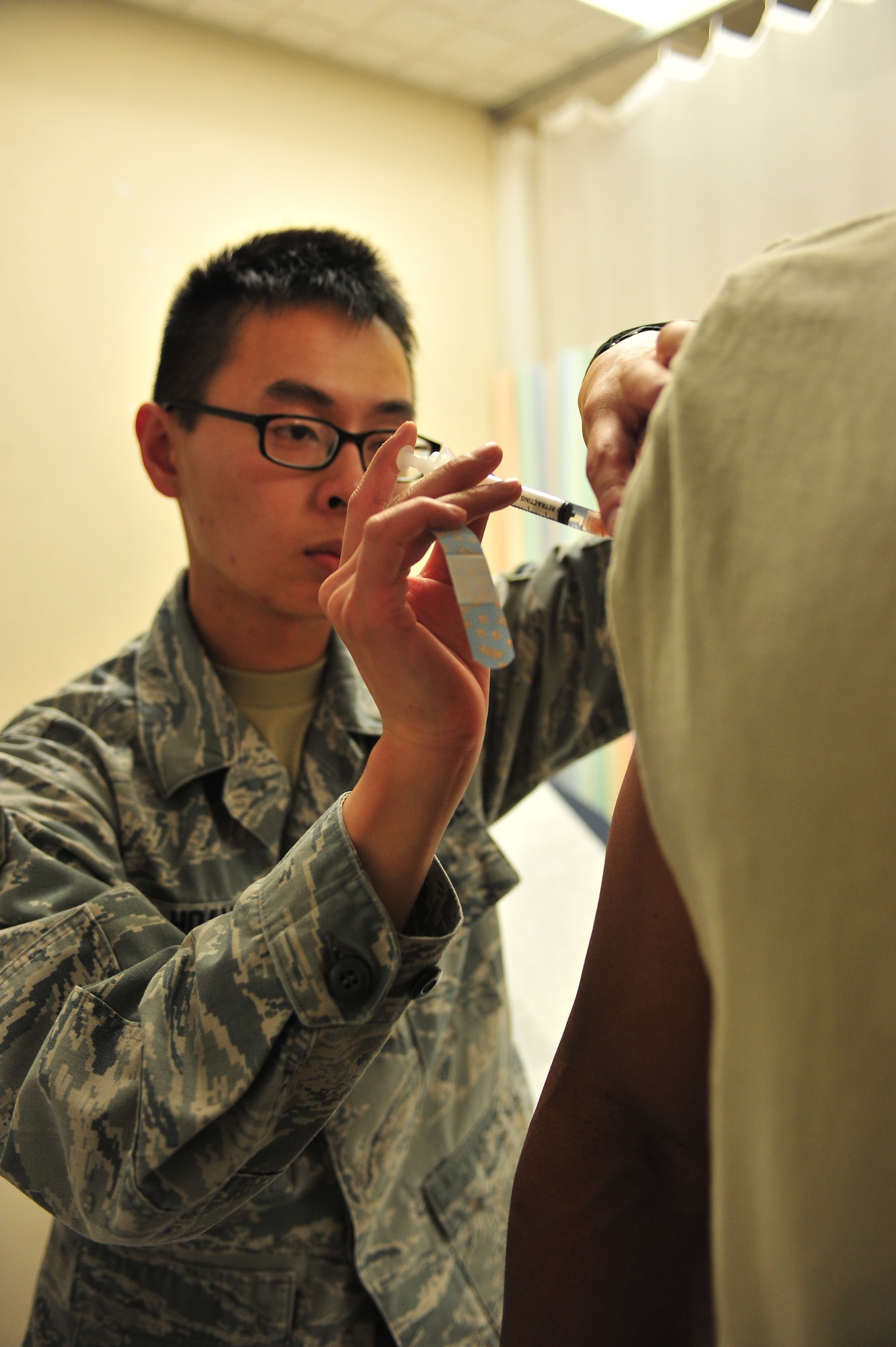 Senior Airman David Hoang, 5th Medical Operations Squadron allergy and immunizations technician, gives a patient a shot at Minot Air Force Base, N.D., Sept. 16, 2015. The Immunization Clinic offers immunizations for viruses such as the flu and smallpox as well as allergy relief and pediatric shots. (U.S. Air Force photo/Senior Airman Stephanie Morris)