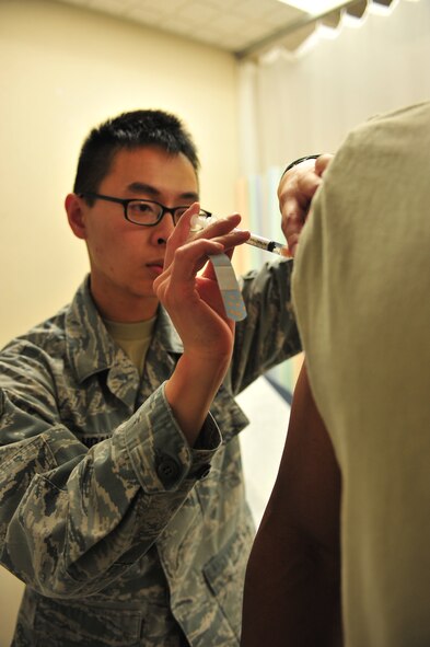 Senior Airman David Hoang, 5th Medical Operations Squadron allergy and immunizations technician, gives a patient a shot at Minot Air Force Base, N.D., Sept. 16, 2015. The Immunization Clinic offers immunizations for viruses such as the flu and smallpox as well as allergy relief and pediatric shots. (U.S. Air Force photo/Senior Airman Stephanie Morris)