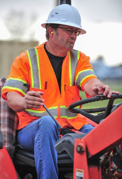William Marier, contractor, drives an excavator while building a new sidewalk at Minot Air force Base, N.D., Sept. 17, 2015. The sidewalk is for the airfield lighting system building which is also receiving new sewer systems, an updated internal structure, new sidewalks and electrical systems. (U.S. Air Force photo/Senior Airman Stephanie Morris)