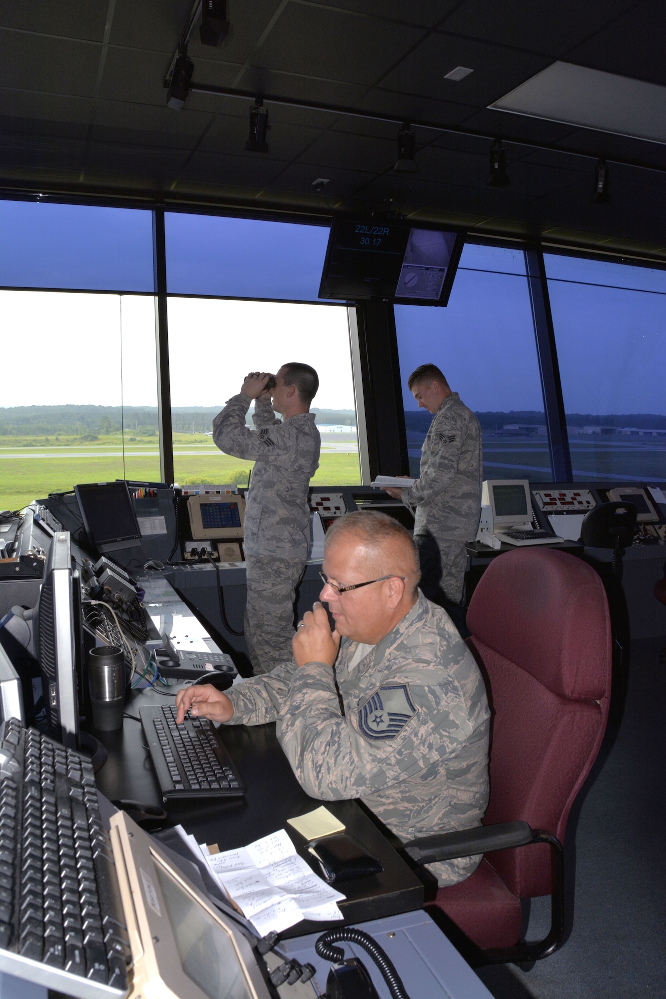 U.S. Air Force Master Sgt. Tony L. Parker, tower watch supervisor for the 235th Air Traffic Control Squadron issues a Notice to Airmen (NOTAM) with Lockheed Martin Flight Services for C-130 aircraft night operations training as Staff Sgt. Justin W. Condon, a local controller for airborne aircraft looks for aircraft arriving from the east. Senior Airman James D. Bellissimo, ground controller, consults regulations for a precision approach radar alignment during daily operations, July 8, 2015 at Stanly County Airport, New London, N.C. (U.S. Air National Guard photo by Master Sgt. Patricia F. Moran, 145th Public Affairs/Released)