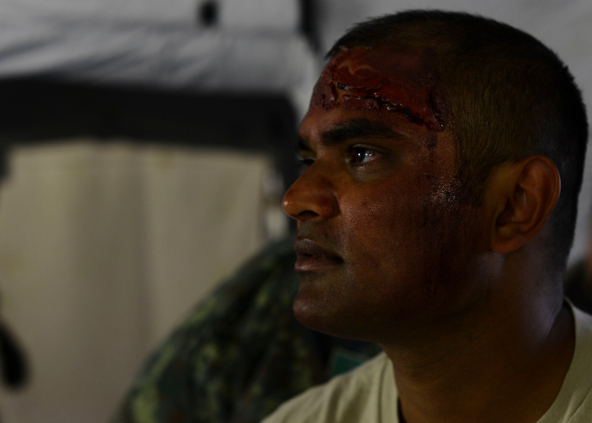 U.S. Air Force Staff Sgt. Dinesh Sheonath, 86th Medical Support Squadron war reserve material inventory management NCO in charge, awaits simulated treatment for a fake injury during the Expeditionary Medical Support training for exercise Immediate Response 15. Exercise IR 15 is designed to enhance regional stability, strengthen partnership capacities and improve interoperability between partner nations. (U.S. Air Force photo by Senior Airman Austin Harvill/Released)