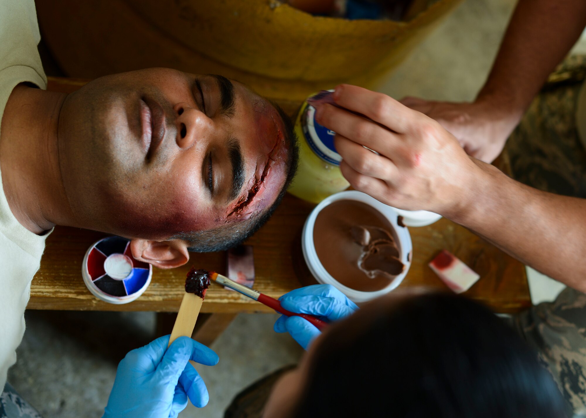 U.S. Air Force Staff Sgt. Dinesh Sheonath, 86th Medical Support Squadron war reserve material inventory management NCO in charge, receives moulage effects during the Expeditionary Medical Support training for exercise Immediate Response 15. Exercise IR 15 is designed to enhance regional stability, strengthen partnership capacities and improve interoperability between partner nations. (U.S. Air Force photo by Senior Airman Austin Harvill/Released)