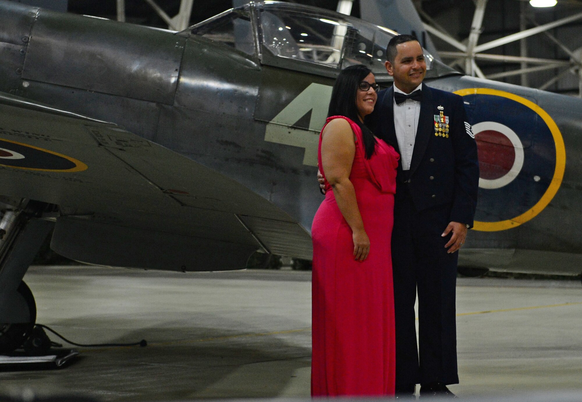 An Airman and his spouse pose for a photo in front of Spitfire Mk XVI TE311 at the Air Force Ball on RAF Lakenheath, England, Sept. 18, 2015. In January 2000,TE311 was delivered to RAF Coningsby for spares recovery, and, after a painstaking rebuild lasting 11 years, the aircraft was returned to an immaculate and extremely authentic standard, and took to the air again in Oct. 2012, for the first time in 58 years. (U.S. Air Force photo by Senior Airman Erin O’Shea/Released)