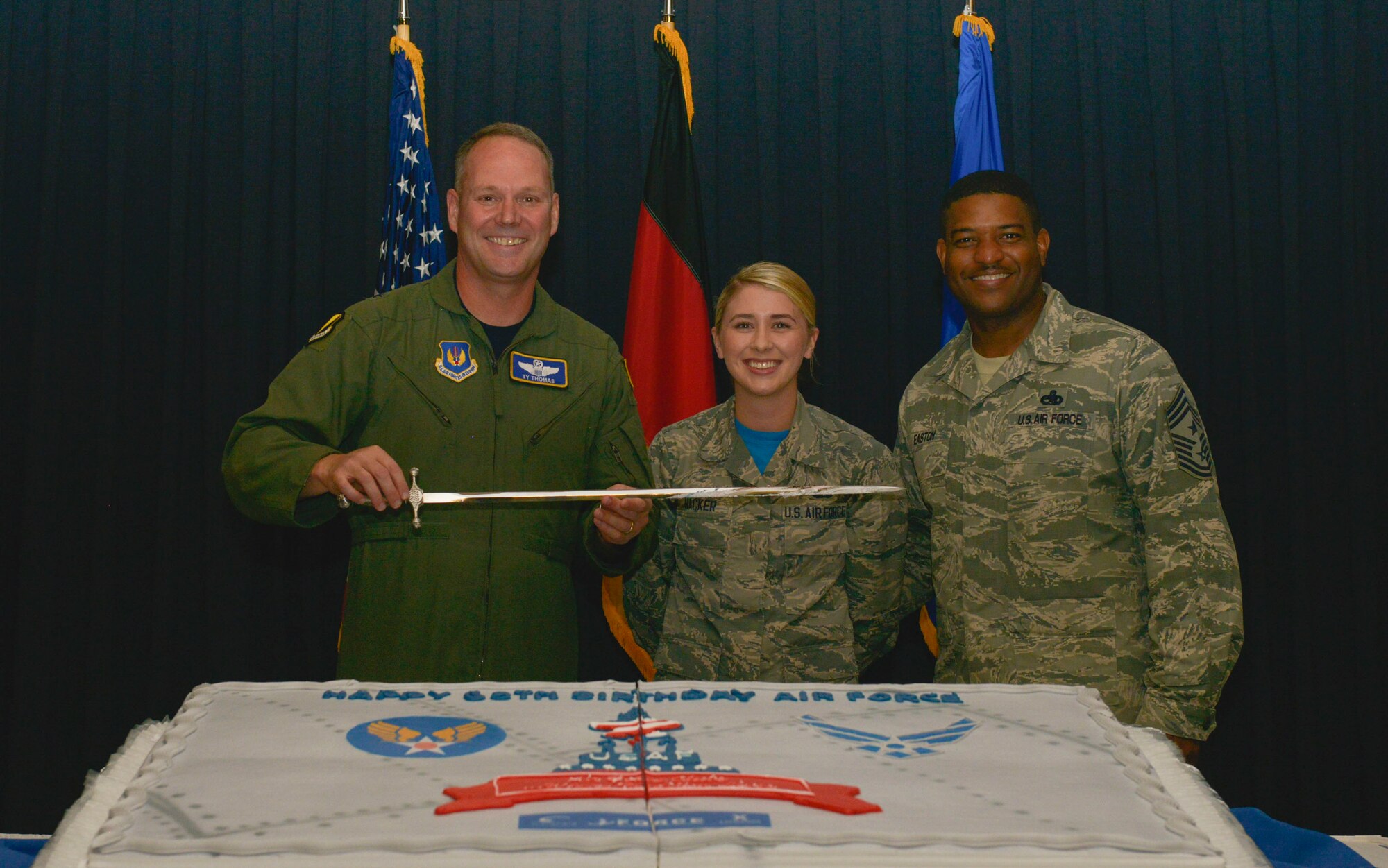Brig. Gen. Jon T. Thomas, 86th Airlift Wing commander, Chief Master Sgt. Phillip L. Easton, 86th AW command chief, and Airman Hannah Hacker, 786th Force Support Squadron retentions and separations technician, pose for a photo after cutting the celebratory cake during the 68th Air Force Birthday Cake-Cutting ceremony Sept. 18, 2015, at Ramstein Air Base, Germany. It is an Air Force tradition for the highest and the lowest ranking members to cut the cake during Air Force birthday celebrations. 