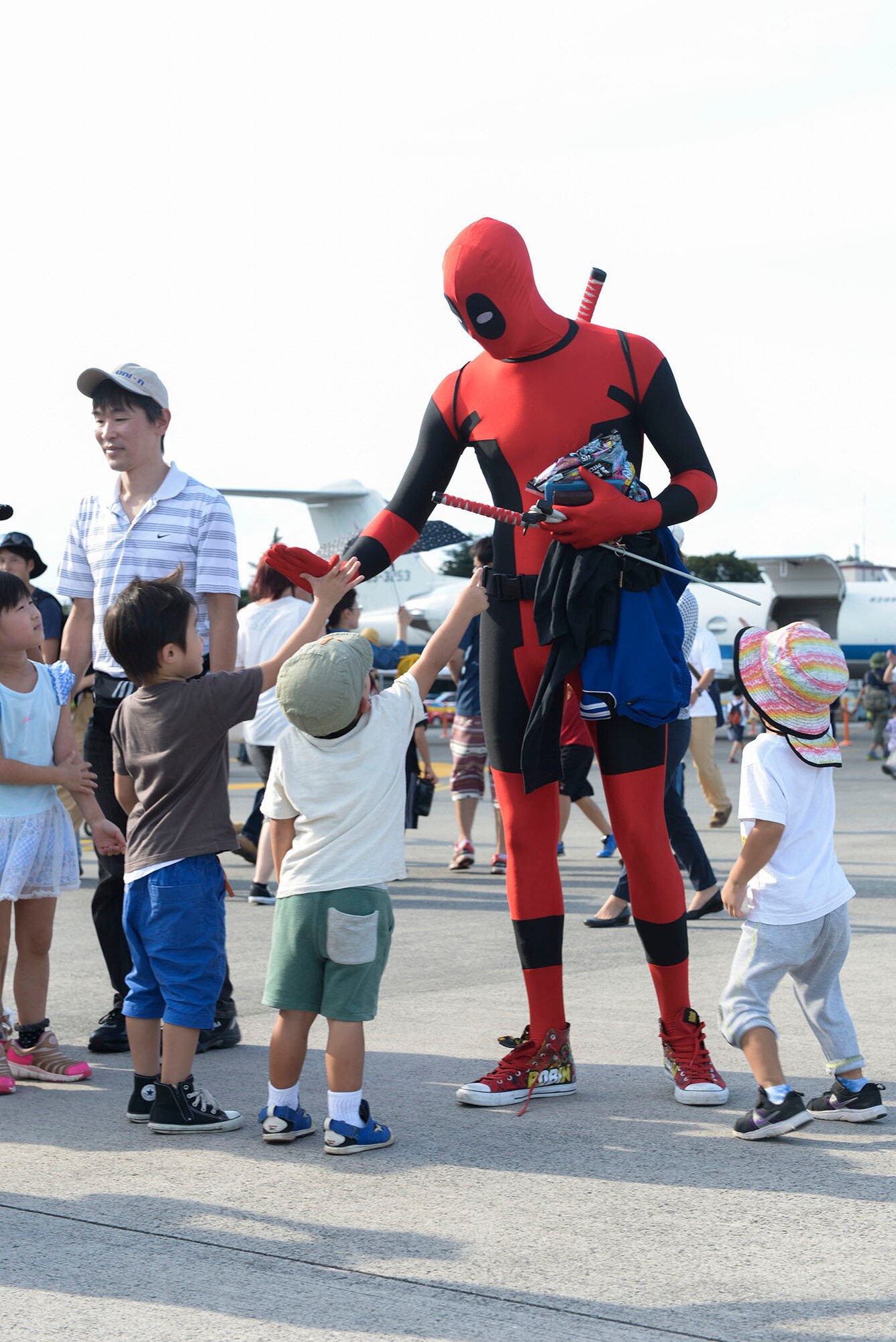 A man in a Deadpool costume high-fives a child during the Japanese-American Friendship Festival at Yokota Air Base, Japan, Sept. 20, 2015. More than 185,000 people attended the annual festival. (U.S. Air Force photo by Staff Sgt. Cody H. Ramirez/ Released)