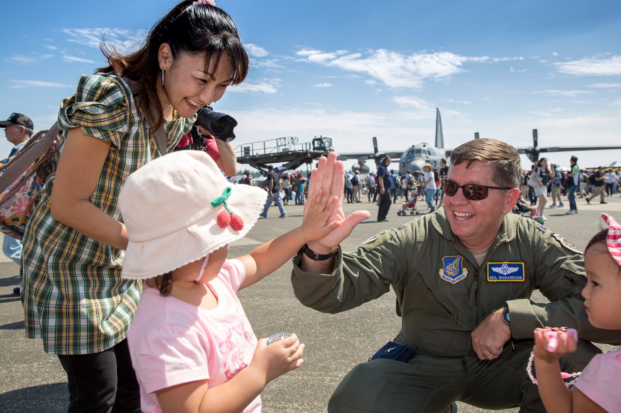 Col. Neil Richardson, 374th Airlift Wing vice commander, high-fived after offering a commemorative coin to local girls during the Japanese-American Friendship Festival at Yokota Air Base, Japan, Sept. 20, 2015. 185,000 visitors attended the festival designed to bolster the bi-lateral relationship shared between the United States and Japan. In addition to static displays and live music, the festival offered a variety of American and Japanese food. (U.S. Air Force photo by Osakabe Yasuo/Released) 