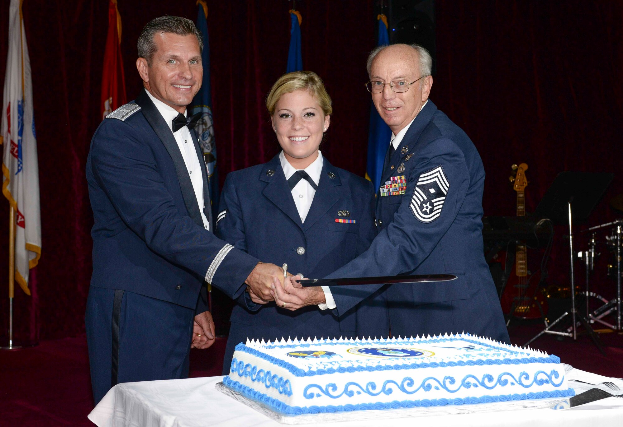 U.S. Air Force Brig. Gen. Barry Cornish, 18th Wing commander, Airman 1st Class Aubrina Fairweather, 18th Civil Engineer Squadron operations manager apprentice, and retired Chief Master Sgt. John W. Perkins cut the cake with a saber during the 2015 Air Force Ball Sept. 19, 2015, at the Rocker NCO Club on Kadena Air Base, Japan. It is a tradition for the youngest and oldest Airmen to cut the cake together to signify respect and honor afforded to experience and seniority while symbolizing the newer generation of Airmen who are filling in the ranks. (U.S. Air Force photo by Senior Airman John Linzmeier)