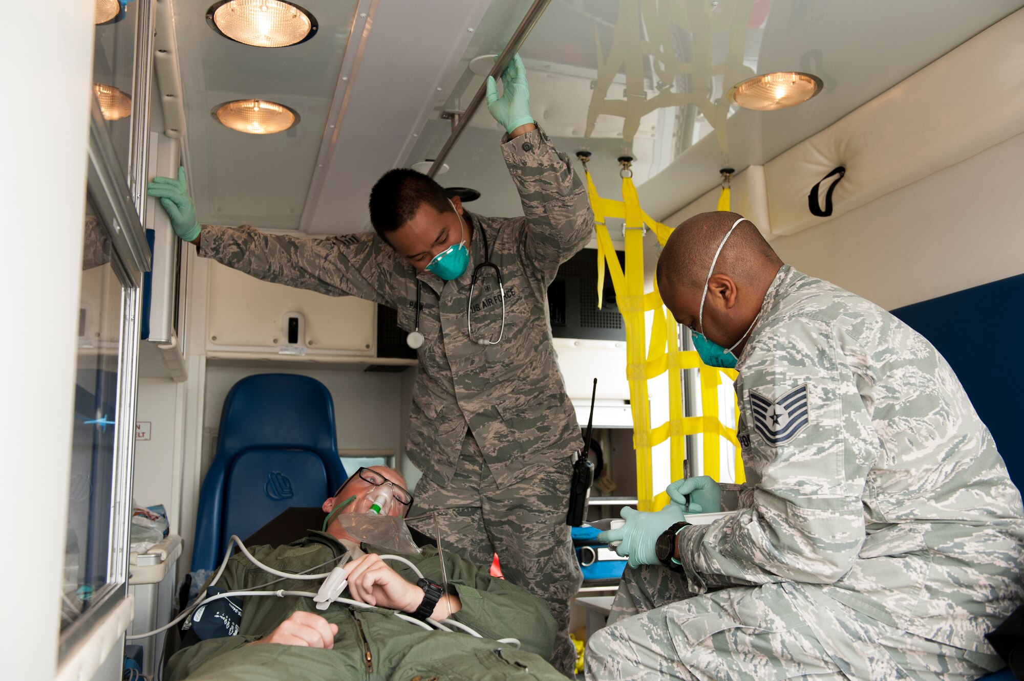 U.S. Air Force Staff Sgt. Chang Park, 18th Aerospace Medicine Squadron aerospace medical technician, along with Tech. Sgt. James Barnett, 18th AMDS NCO in charge of flight medicine, assist a volunteer playing the part of a flight crew member that is ill after returning from a deployment during a medical emergency management exercise Sept. 21, 2015, at Kadena Air Base, Japan. The 18th Medical Group conducted this exercise to test readiness in a disease containment scenario. (U.S. Air Force photo by Airman 1st Class Zackary A. Henry)