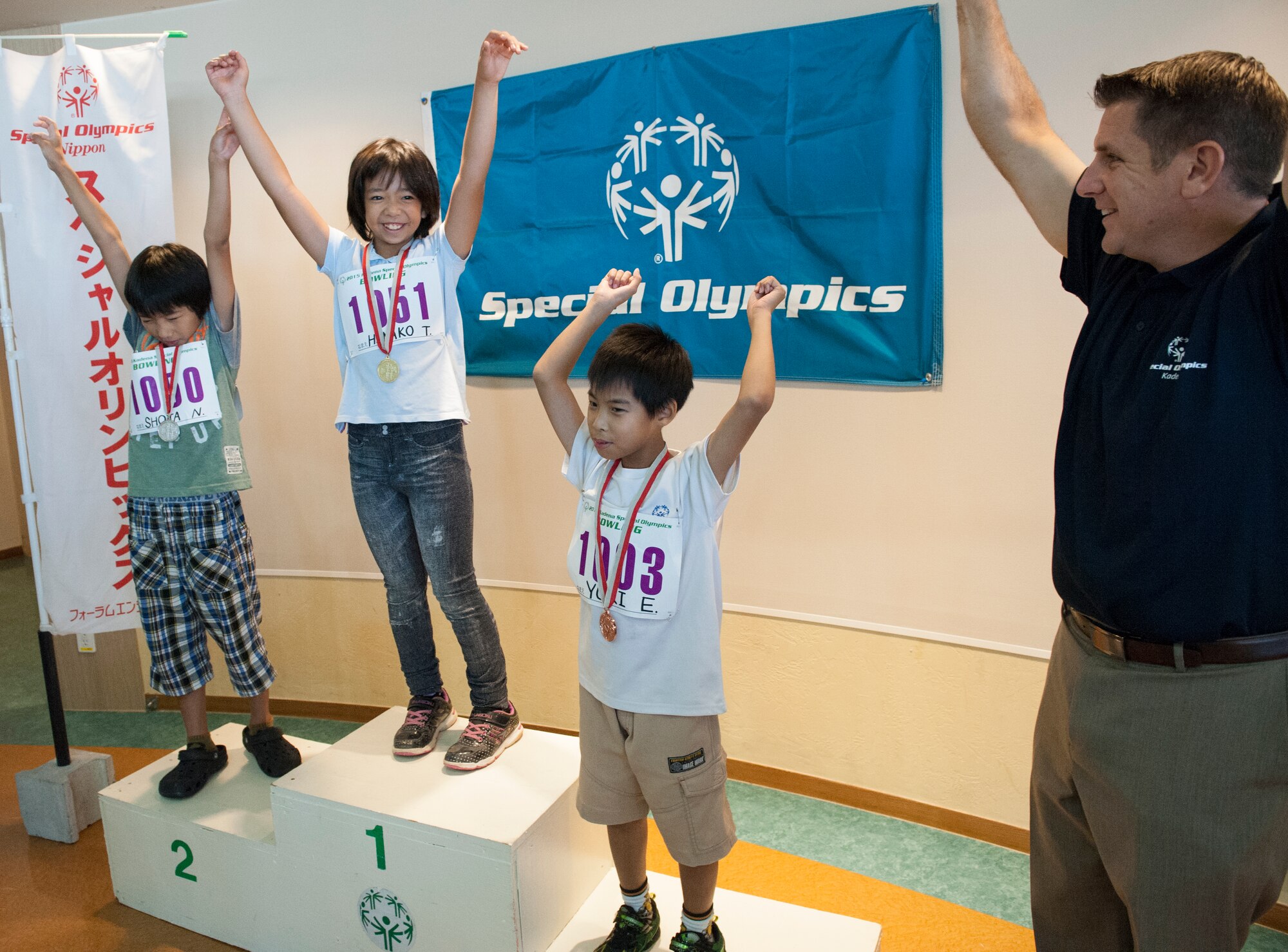 Shota, Hinako and Yuki, Kadena Special Olympics athletes, celebrate getting their medals with U.S. Air Force Col. Christopher Amrhein, 18th Wing vice commander during the KSO bowling event at Enagic Bowling in Mihama, Japan, Sept. 19, 2015. Bowling is the first event in the series of KSO competitions that lead up to the main games on Nov. 7. 
