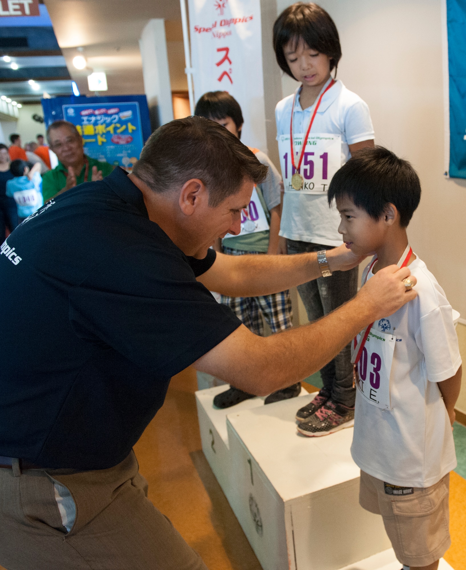 U.S. Air Force Col. Christopher Amrhein, 18th Wing vice commander, puts a third place medal on Yuki, Kadena Special Olympics athlete, during the KSO bowling event at Enagic Bowling in Mihama, Japan, Sept. 19, 2015. Athletes were three to a lane and after two games, the scores were tallied and the medals given. (U.S. Air Force photo by Airman 1st Class Corey M. Pettis)
