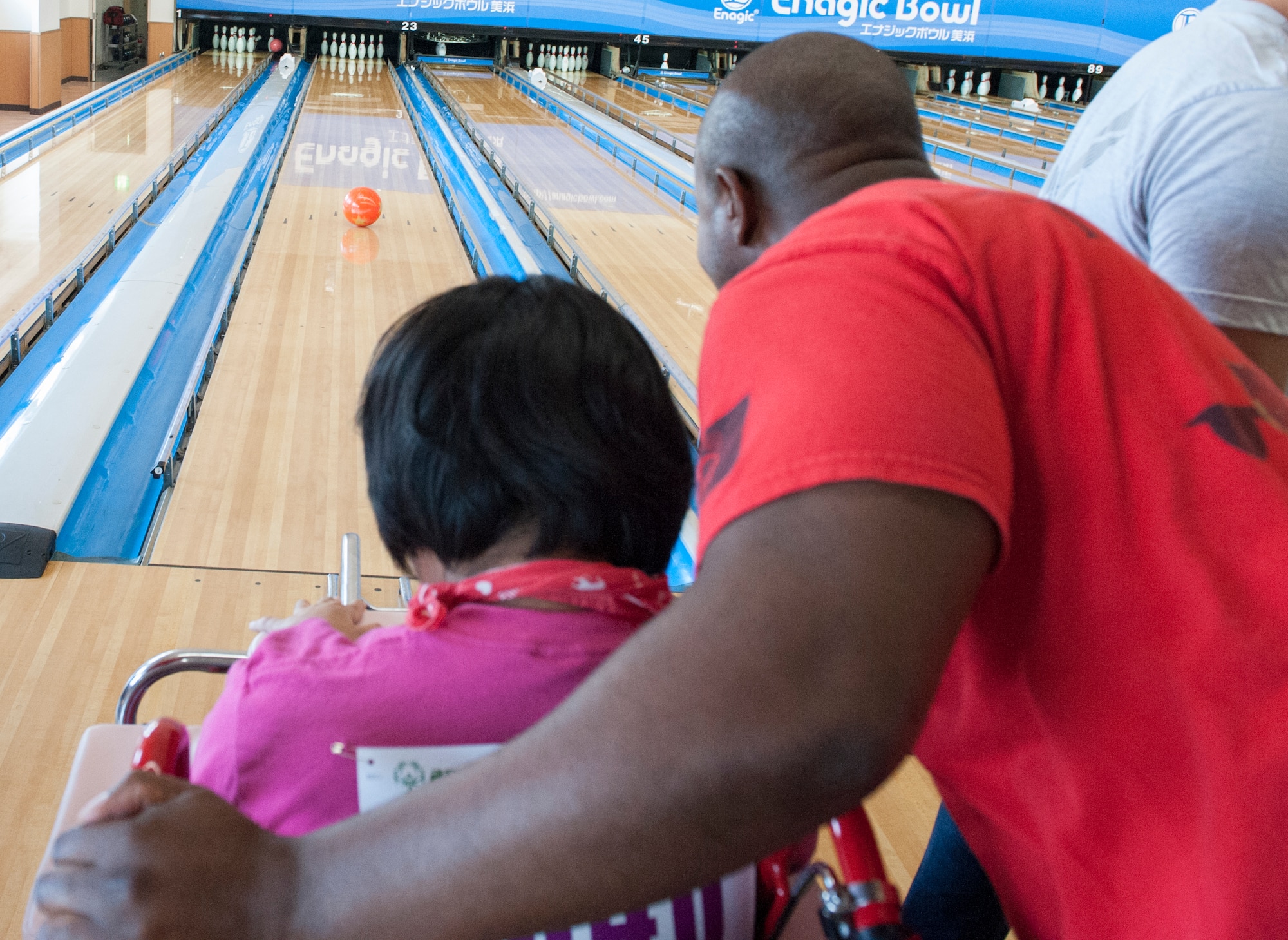 U.S. Air Force Master Sgt. Casey Southern, 909th Air Refueling Squadron boom operator, and Ayami, Kadena Special Olympics athlete, watch the bowling ball roll down the lane during the KSO bowling event at Enagic Bowling in Mihama, Japan, Sept. 19, 2015. Every year, Airmen from Kadena Air Base help organize and promote this community event for people with disabilities. (U.S. Air Force photo by Airman 1st Class Corey M. Pettis)