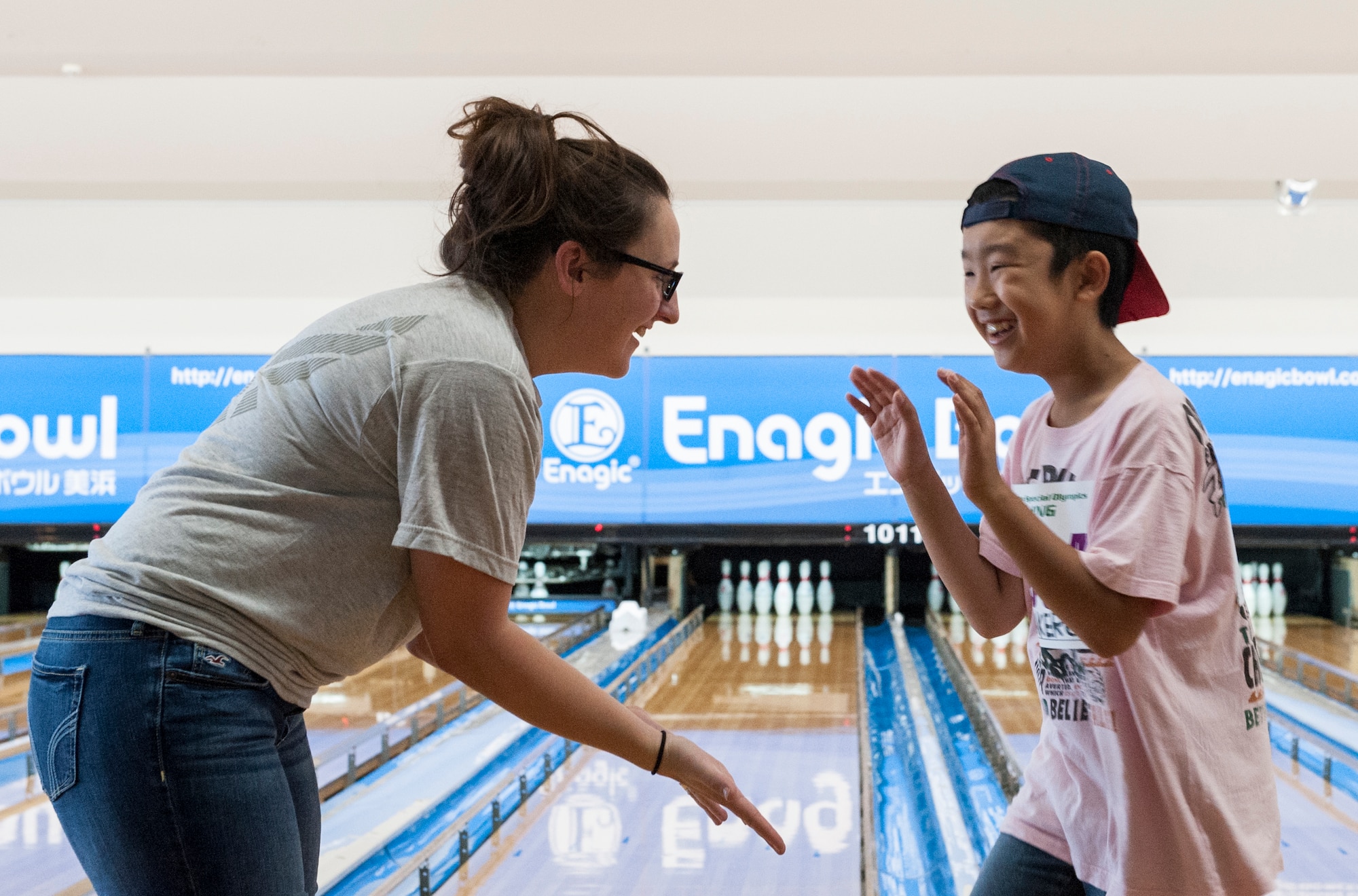 U.S. Air Force Staff Sgt. Rachel McCoy, 18th Logistic Readiness Squadron central storage supervisor, and Yuto, Kadena Special Olympics Athlete, high five each other after Yuto rolls the bowling ball during the KSO bowling event at Enagic Bowling in Mihama, Japan, Sept. 19, 2015. Airmen from Kadena Air Base volunteered to fill each lane and assist the athletes as they bowled. (U.S. Air Force photo by Airman 1st Class Corey M. Pettis)