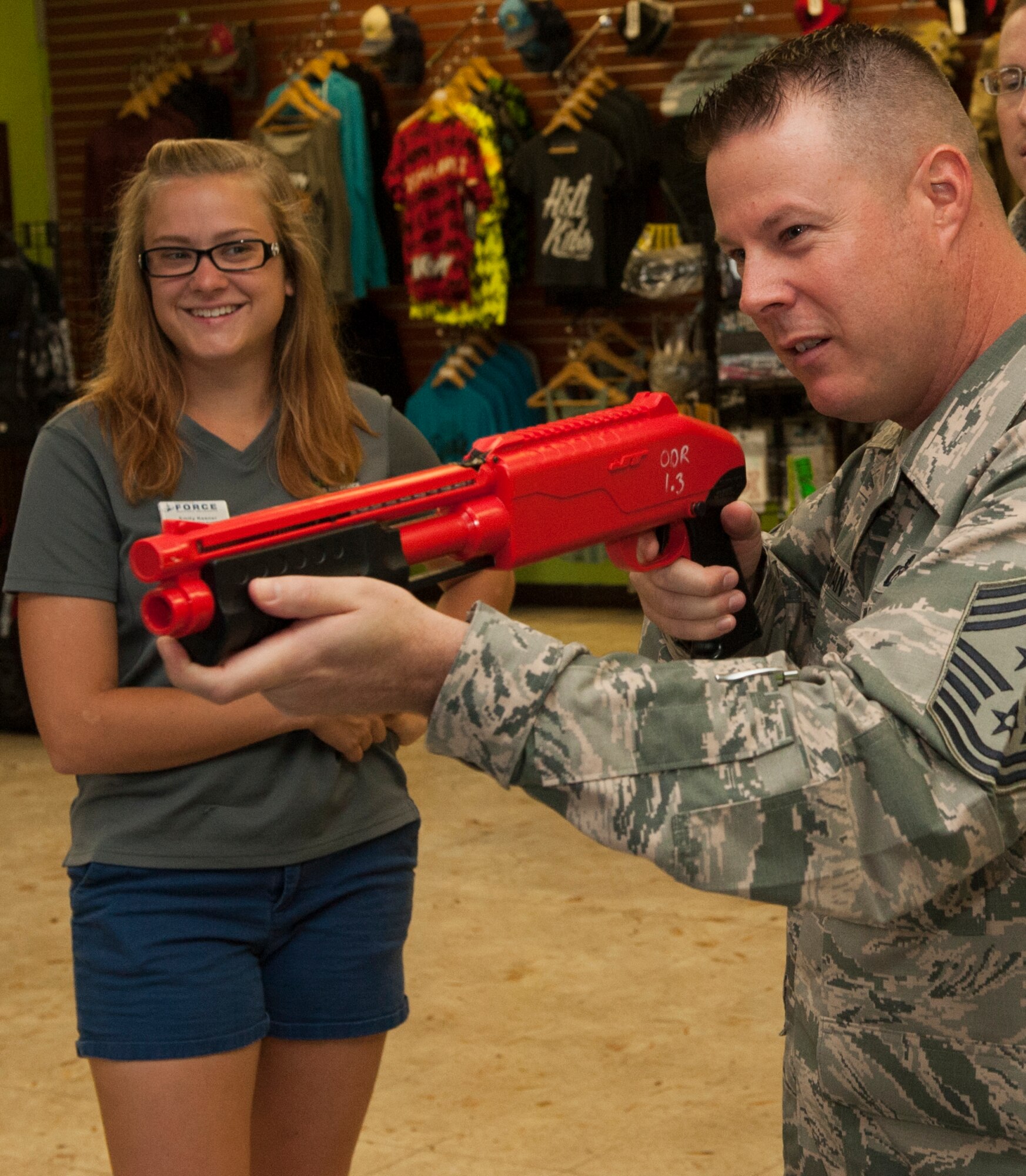 Emily Keener, Outdoor Recreation lead recreation assistant, watches Chief Master Sgt. Charles Hoffman, 18th Wing command chief, use a pump-action paintball gun while visiting Outdoor Recreation for Project 22 Sept. 21, 2015, on Kadena Air Base, Japan. Project 22 is an initiative to show how different programs can help Airmen with resilience in an effort to mitigate suicide. (U.S. Air Force photo by Airman 1st Class Corey M. Pettis)