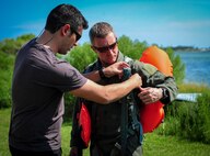 Senior Airman Justin Covieo, 1st Special Operations Support Squadron survival, evasion, resistance and escape specialist, adjusts the harness of during fixed-wing survival training Senior Master Sgt. Ron Riff, 4th Special Operations Squadron superintendent at Hurlburt Field, Fla., Sept. 1, 2015. Aircrew members participate in fixed-wing water survival training tri-annually to maintain proficiency on skill sets such as canopy disentanglement, parachute drop and drag and life raft boarding. (U.S. Air Force photo by Senior Airman Meagan Schutter)