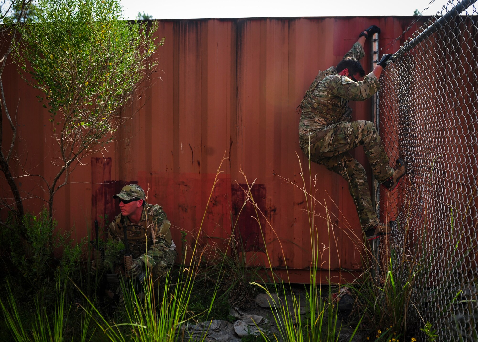 Senior Airman Justin Covieo, 1st Special Operations Squadron survival, evasion, resistance and escape specialist, demonstrates how to climb over a chain link fence during urban clearing training at Eglin Field Complex, Fla., Sept. 2, 2015. Aircrew members participate in combat survival training tri-annually to maintain proficiency on skill sets such as combative, evasion, navigation, signaling, radio use and discipline and contact procedures. (U.S. Air Force photo by Senior Airman Meagan Schutter)
