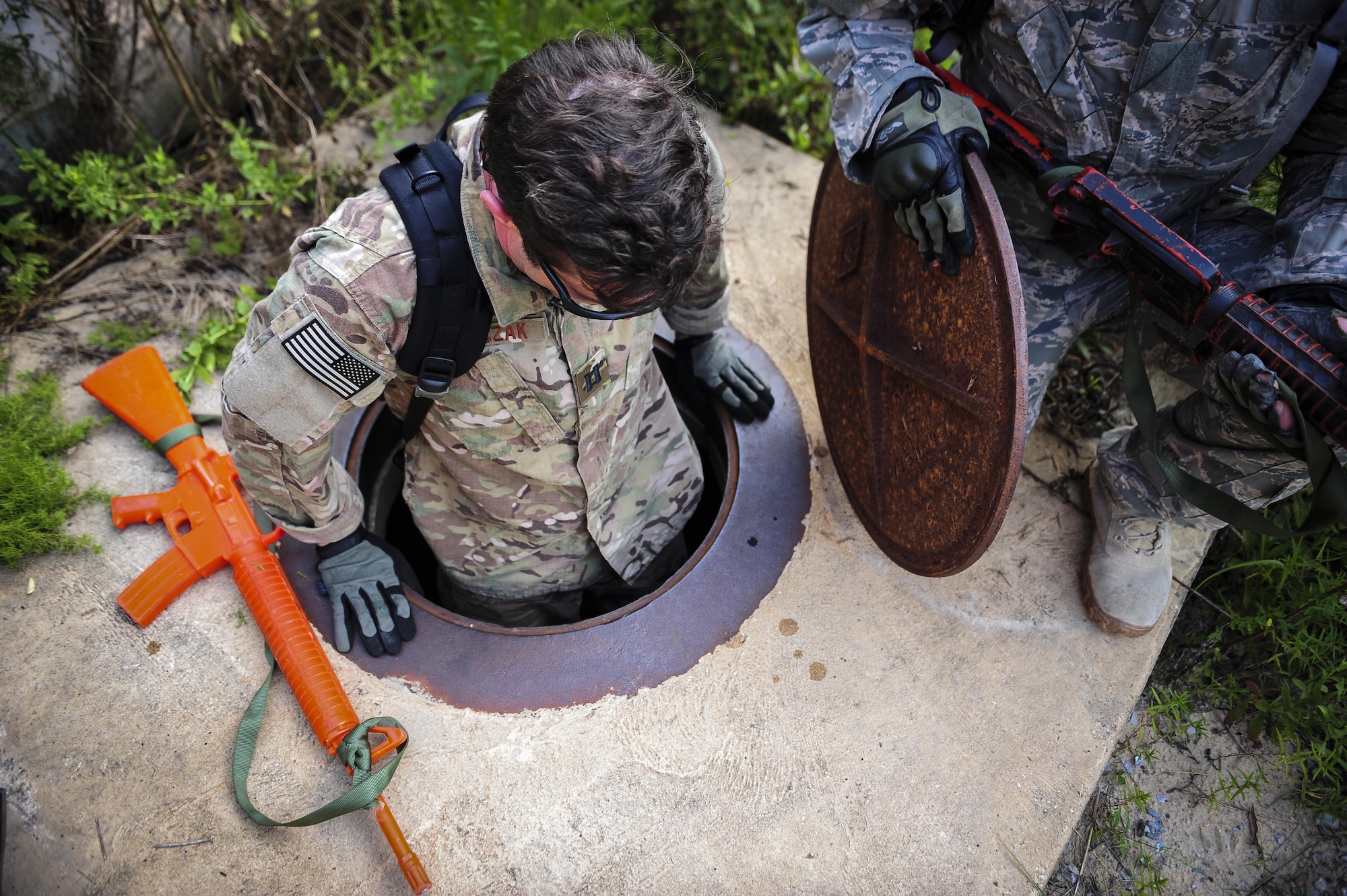 Capt. Joe Tomczak, 4th Special Operations Squadron pilot, climbs into a manhole during urban clearing at Eglin Field Complex, Fla., Sept. 2, 2015. Aircrew members participate in combat survival training tri-annually to maintain proficiency on skill sets such as combative, evasion, navigation, signaling, radio use and discipline and contact procedures. (U.S. Air Force photo by Senior Airman Meagan Schutter)