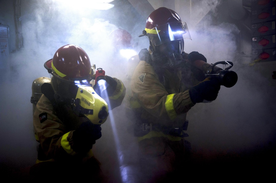 Navy Petty Officer 3rd Class R. Berens, left, and Fireman D. Barber fight a simulated fire during a drill aboard the USS Harry S. Truman in the Atlantic Ocean, Sept. 21, 2015. Berens and Barber are damage controlmen. U.S. Navy photo by Petty Officer 3rd Class A.A. Cruz