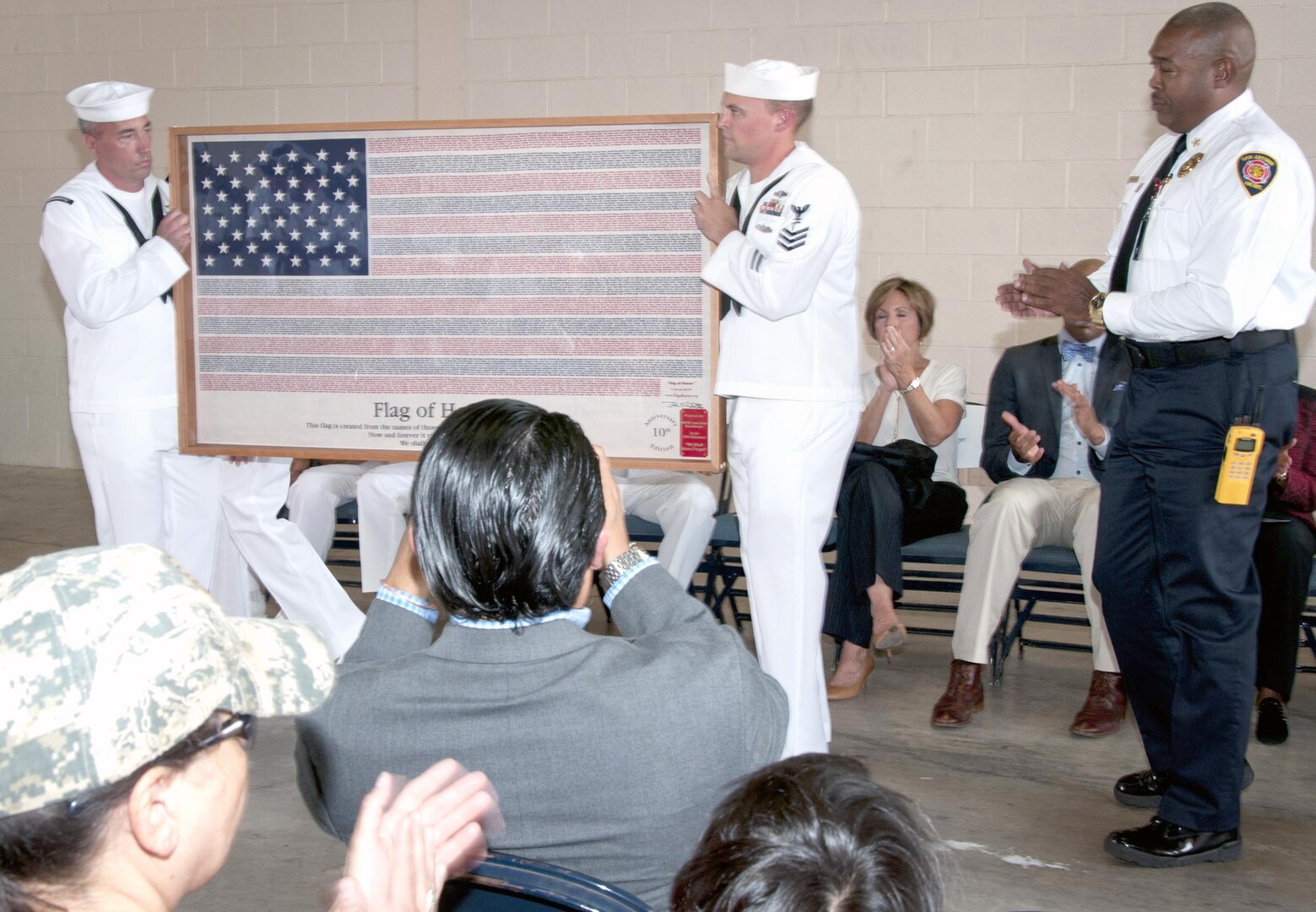 Sailors from the Navy Medicine Training Support Center at Joint Base San Antonio-Fort Sam Houston present San Antonio Fire Chief Charles Hood (right) with a flag of honor at a 9/11 commemoration ceremony at San Antonio Fire Station 1 Sept. 11. The flag includes the names of those who lost their lives during the events of 9/11 and was presented on behalf of the 2015 NMTSC chief petty officer selects.