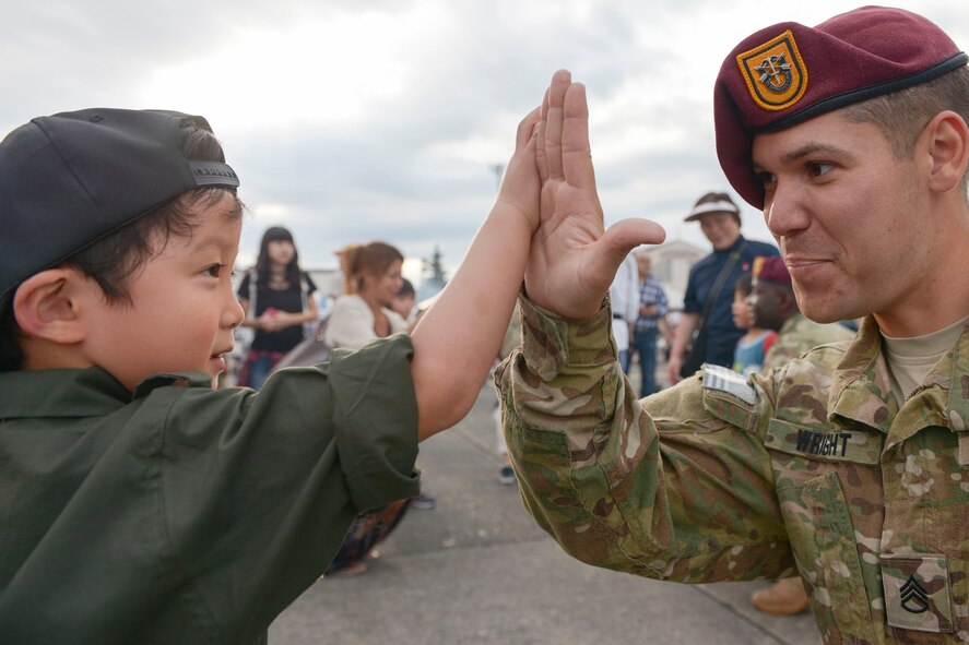U.S. Army Staff Sgt. Brian Wright, 1st Batallion, 1st Special Forces Group (Airborne), high-fives a child during the 2015 Japanese-American Friendship Festival at Yokota Air Base, Japan, Sept. 20, 2015. Wright and other members of his unit jumped from C-130 Hercules during an aerial demonstration at the festival. (U.S. Air Force photo by Staff Sgt. Cody H. Ramirez/Released)