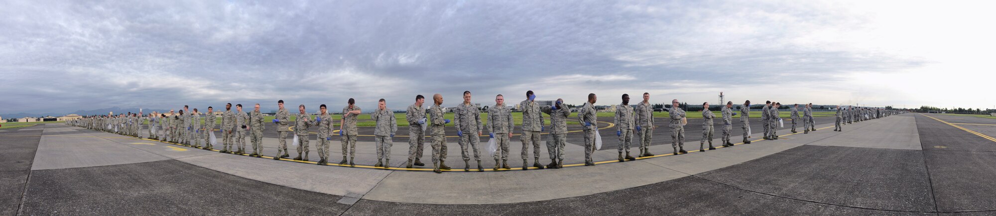 Airmen prepare to perform a foreign object debris walk Sept. 21, 2015, at Yokota Air Base, Japan. FOD is any object potentially harmful to an aircraft, ranging from bolts, screws and other metal pieces, to rocks, paper and plastic. FOD can cost the Air Force millions of dollars in avoidable aircraft damage. Adobe Photoshop was used to merge multiple photos to create a panoramic. (U.S. Air Force illustration by Airman 1st Class Delano Scott/Released)